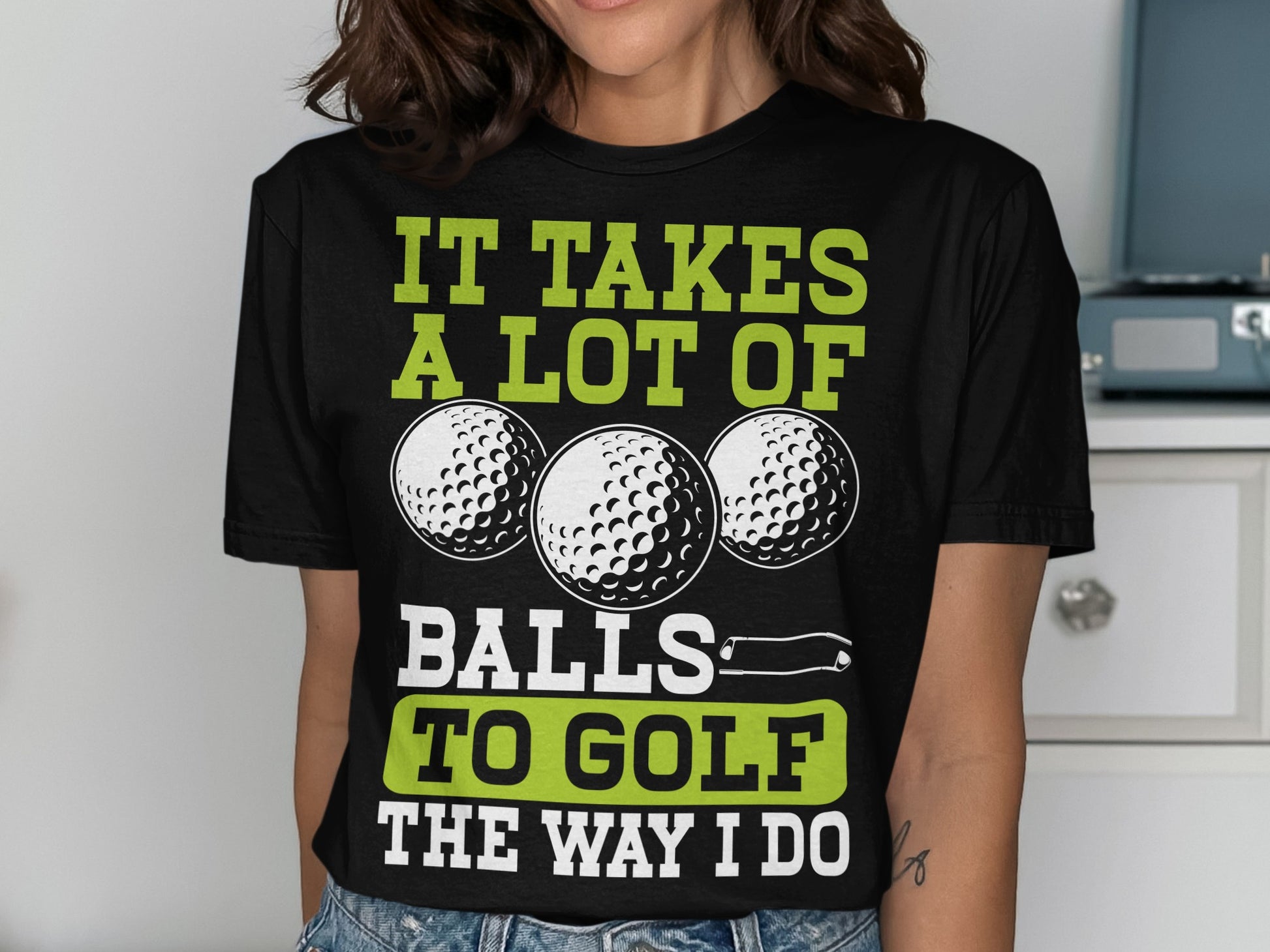 Black t-shirt with green text "IT TAKES A LOT OF BALLS TO GOLF THE WAY I DO" and three golf balls.