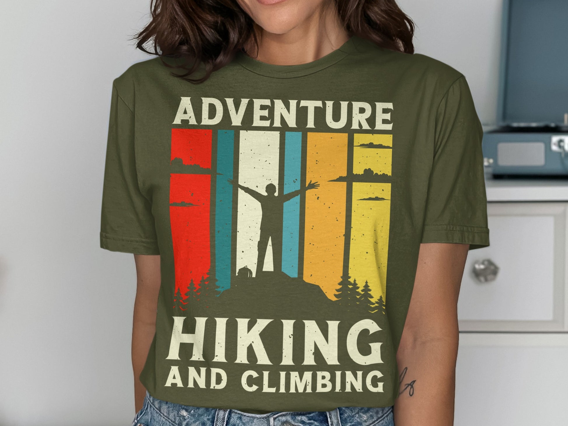 T-shirt graphic with mountain hiker, trees, and text "Adventure Hiking and Climbing".