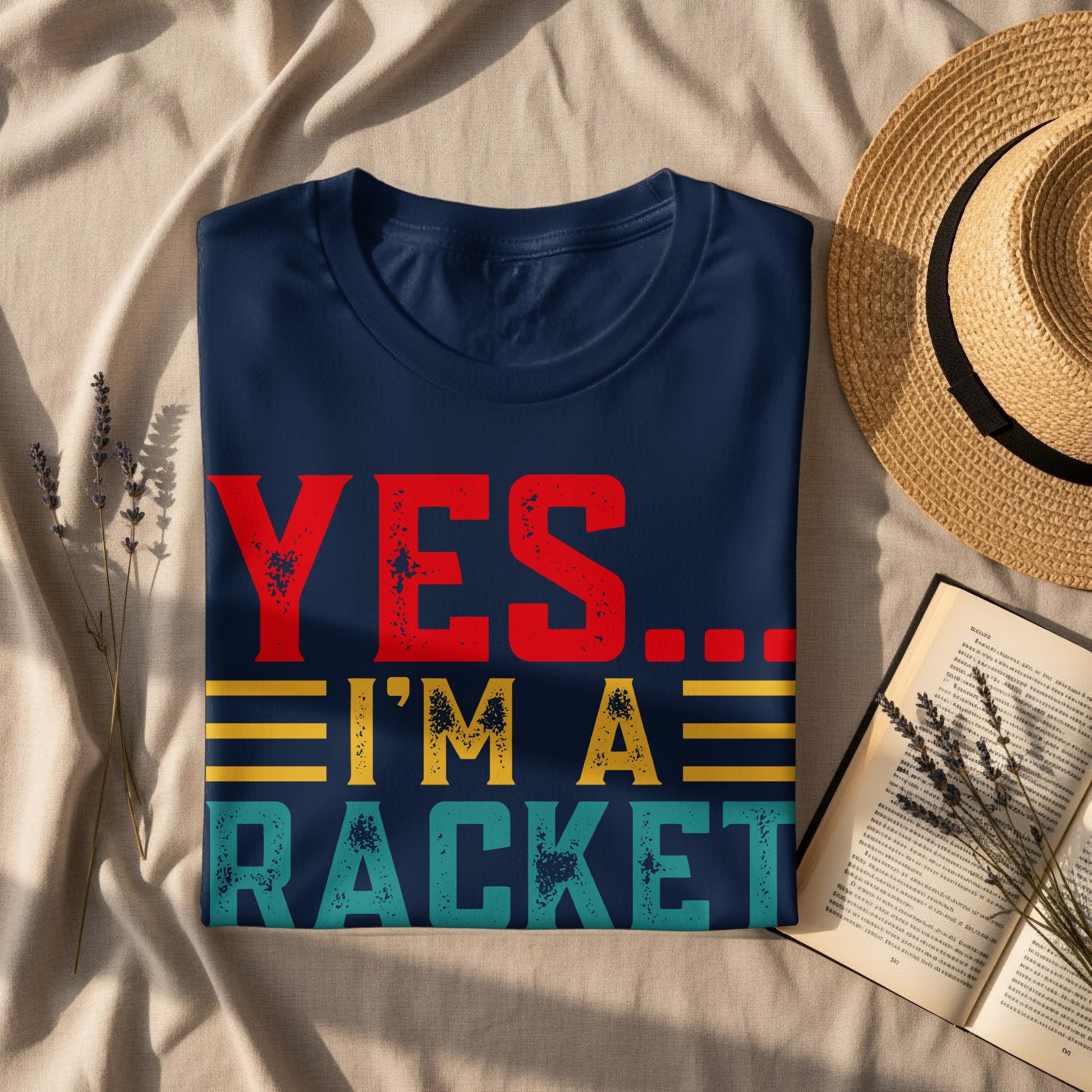 Navy t-shirt with "YES... I'M A RACKET" text, laid flat with straw hat.