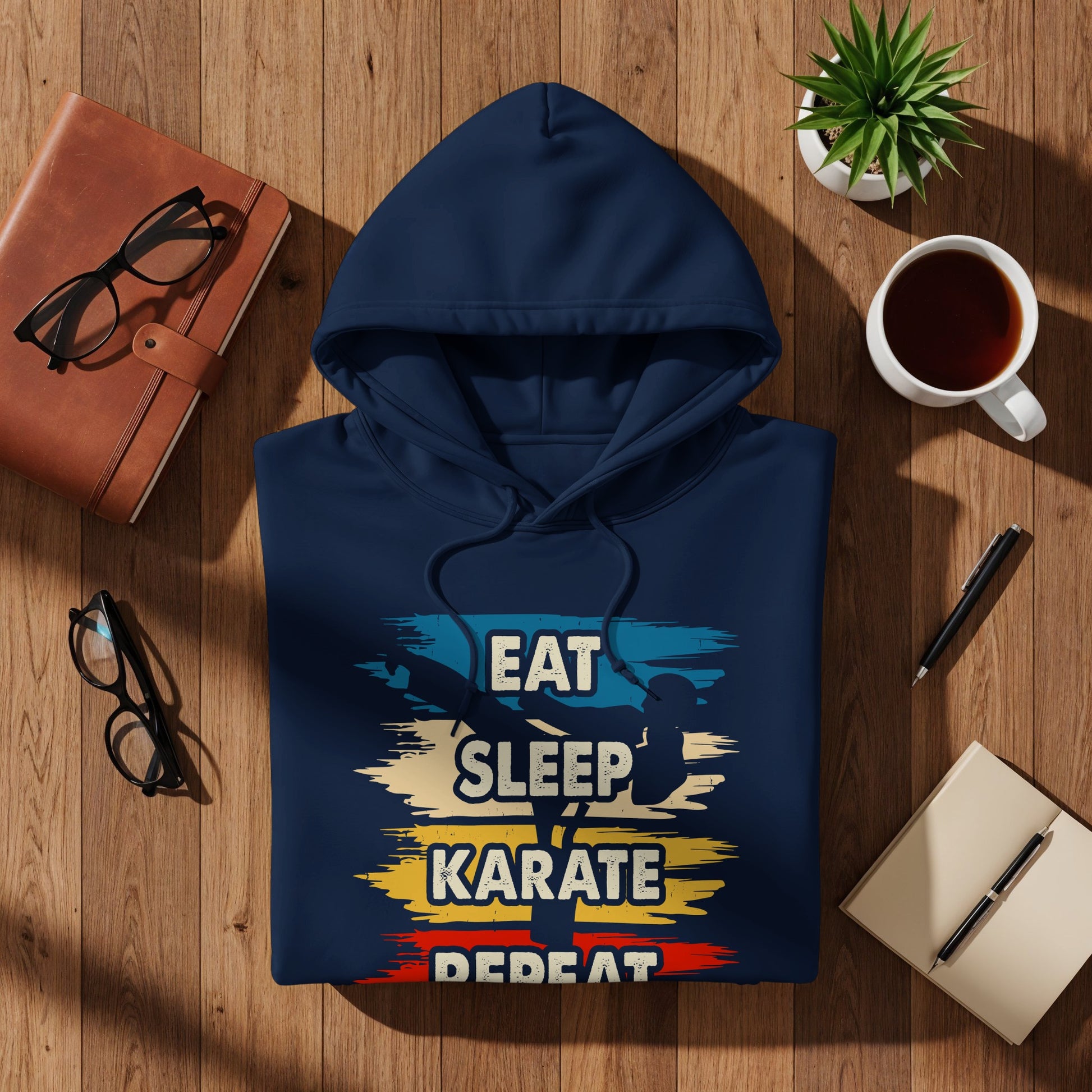 Navy blue hoodie with "Eat Sleep Karate Repeat" graphic on wooden surface.