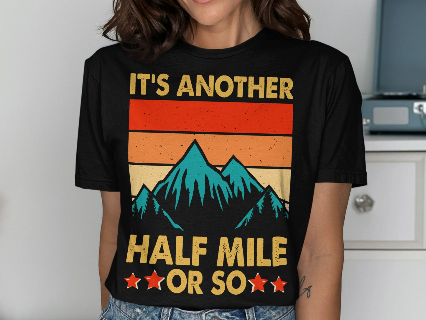 Black t-shirt with "IT'S ANOTHER HALF MILE OR SO" and mountain graphic.