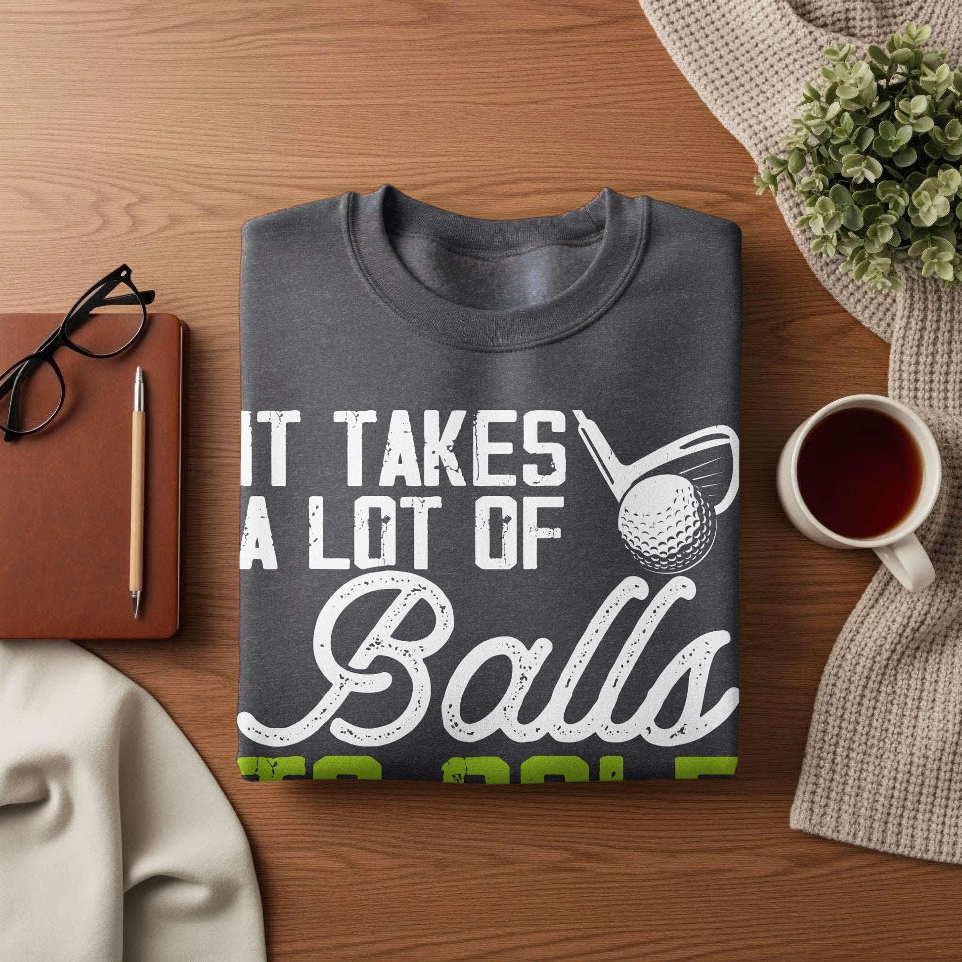 Dark gray sweatshirt with white text "IT TAKES A LOT OF Balls" and golf imagery.