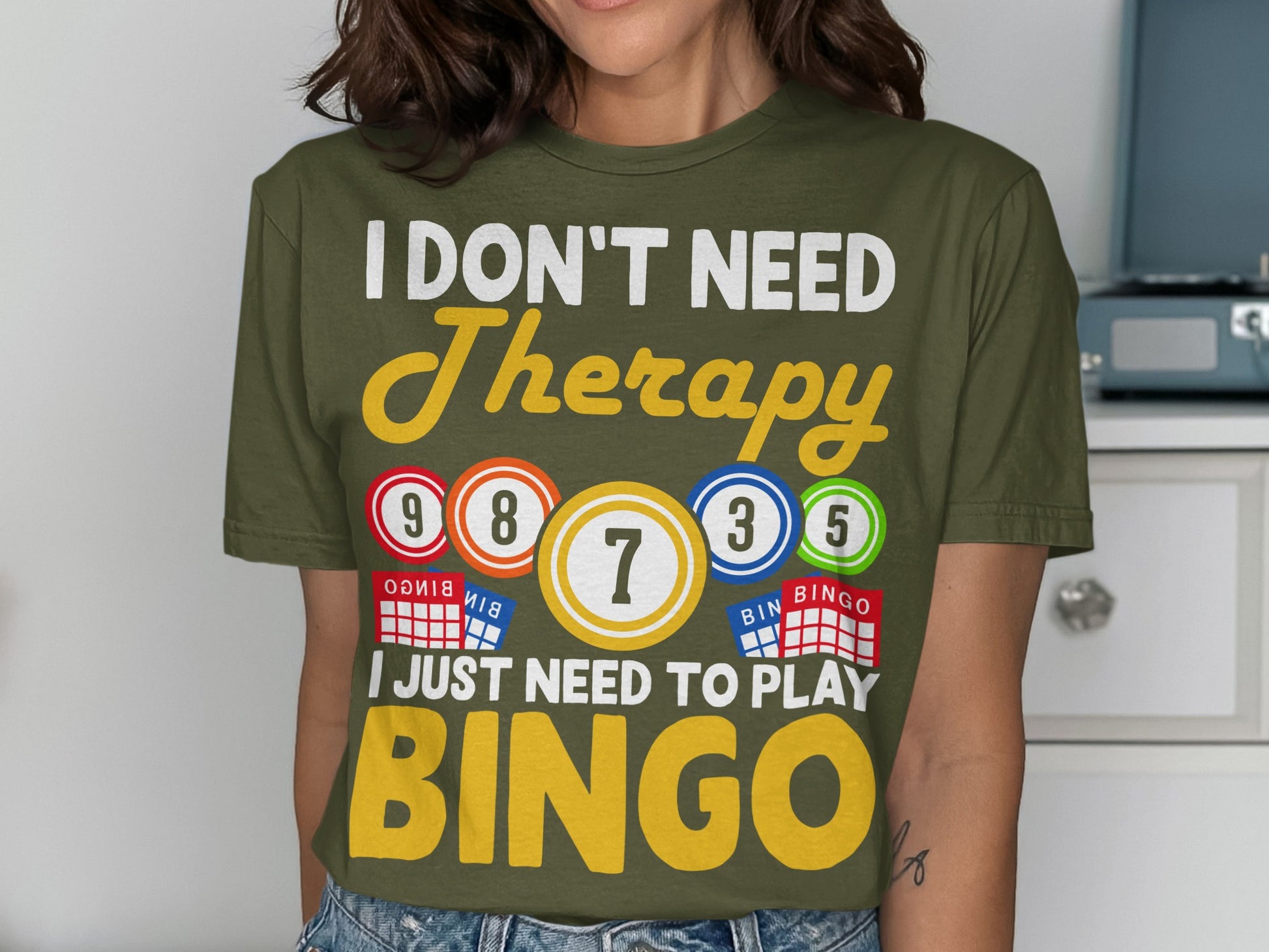 Olive green t-shirt with "I DON'T NEED Therapy BINGO" text and bingo balls.
