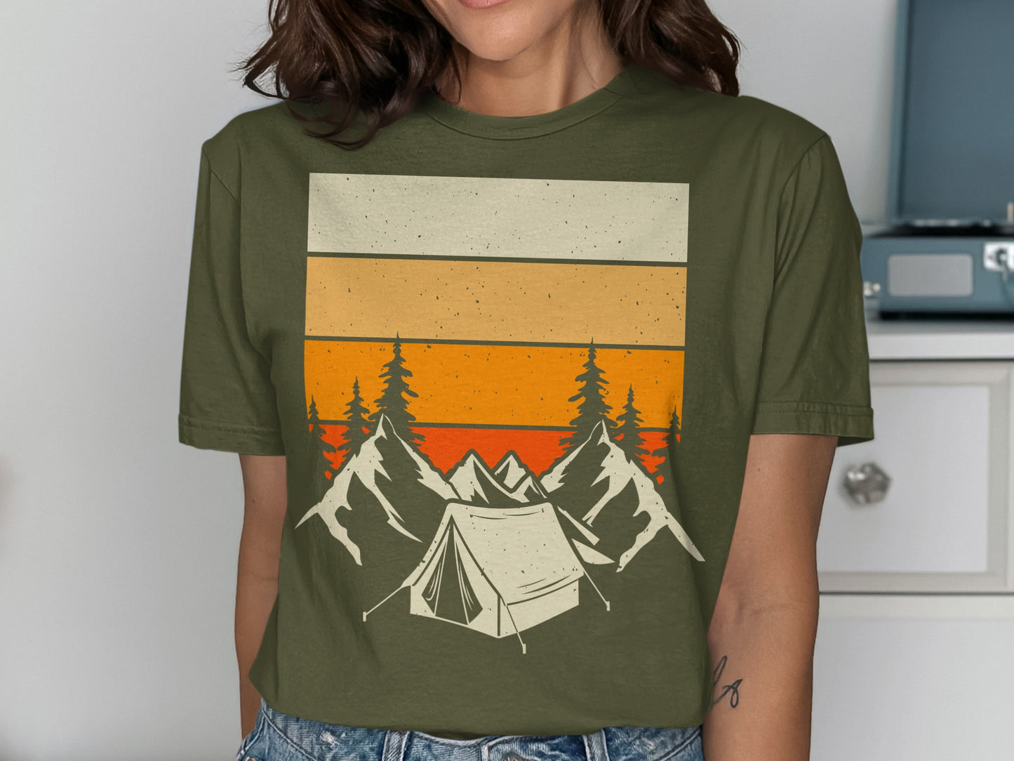 Green t-shirt with a vintage landscape design of a tent and mountains.