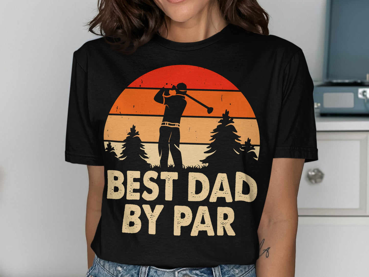 T-shirt with golfer silhouette and "Best Dad By Par" text against sunset and trees.