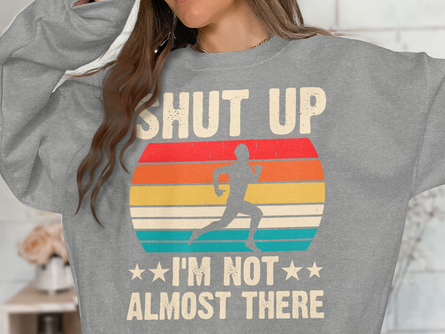 Gray sweatshirt with runner graphic and text: "SHUT UP I'M NOT ALMOST THERE".