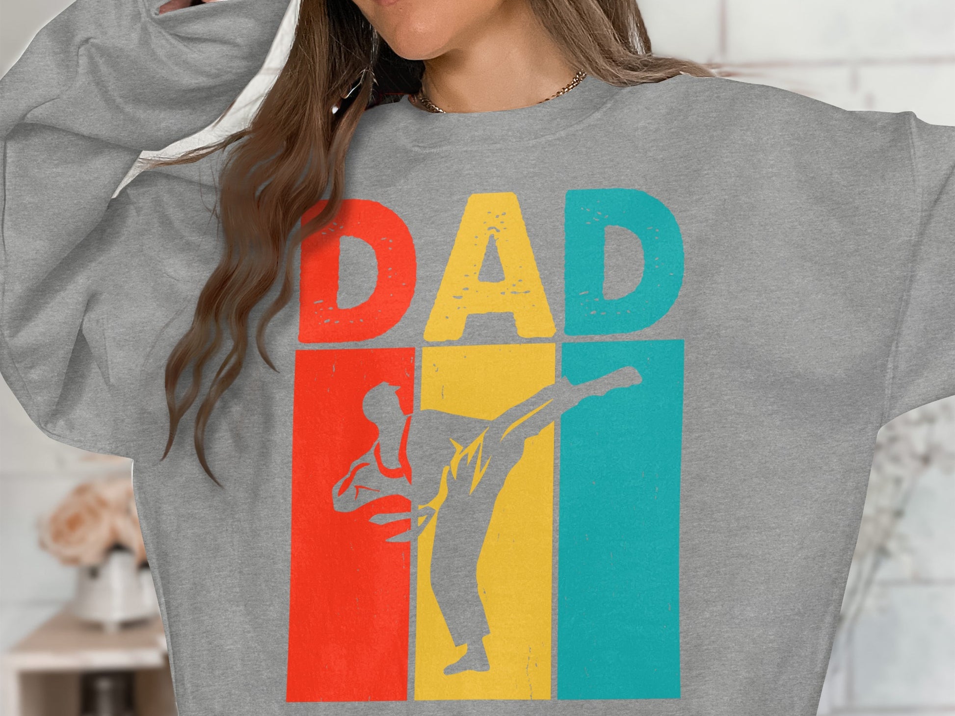 Grey sweatshirt with "DAD" and a martial artist silhouette over a retro color block background.
