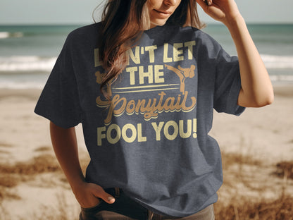 Dark t-shirt with text "DON'T LET THE PONYTAIL FOOL YOU!"