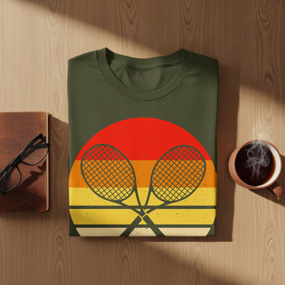 Green t-shirt with crossed tennis rackets on a sunset background.