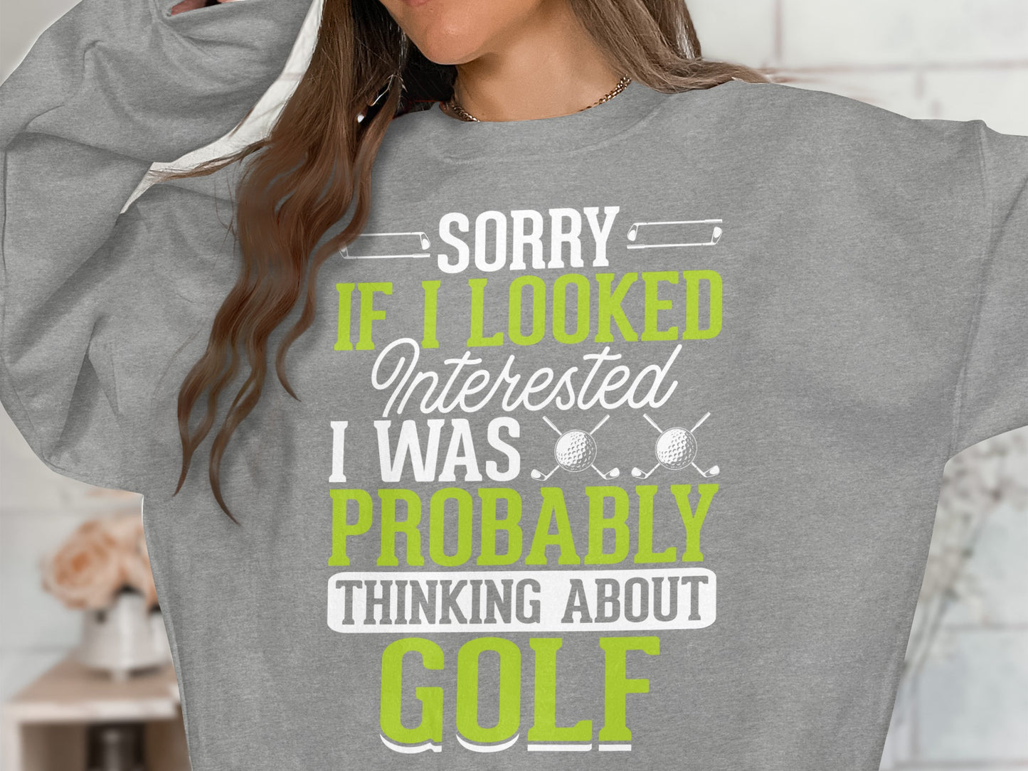 Gray sweatshirt with white and green text: "Sorry if I looked interested I was probably thinking about Golf".