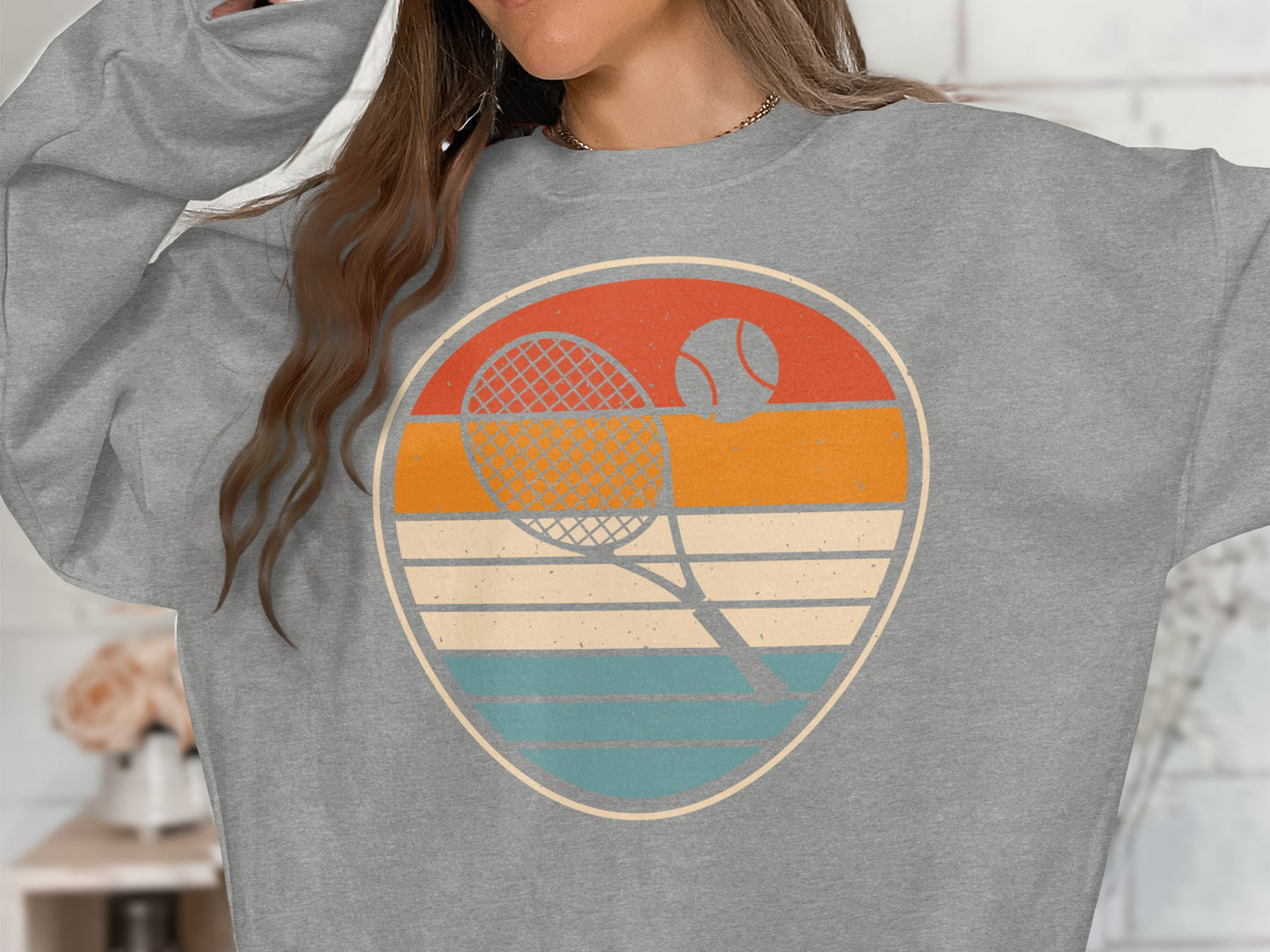 Retro tennis graphic with racket and ball on a grey sweatshirt.