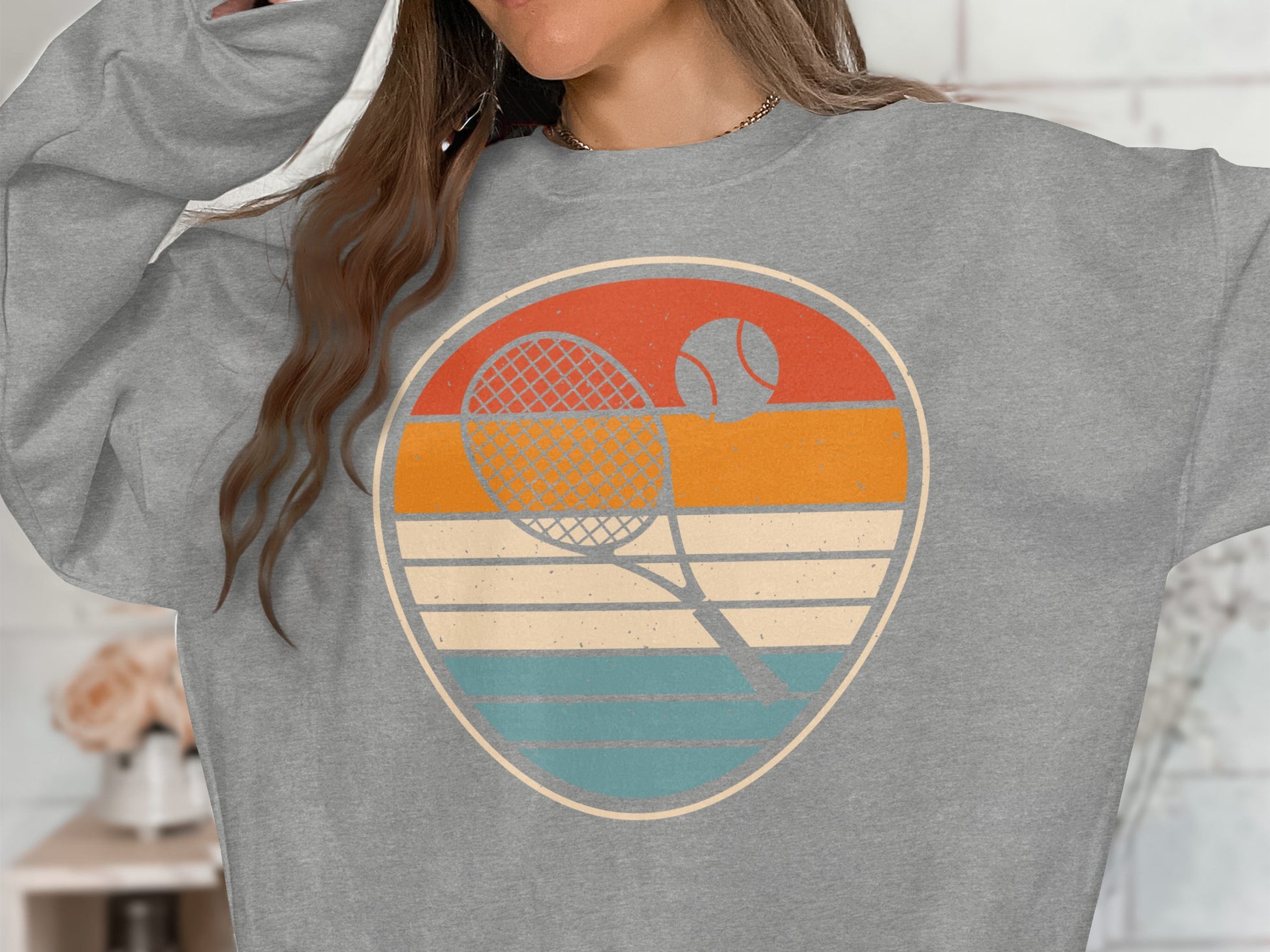 Retro tennis graphic with racket and ball on a grey sweatshirt.