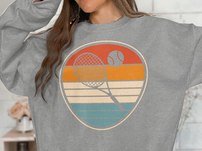 Retro tennis graphic with racket and ball on a grey sweatshirt.