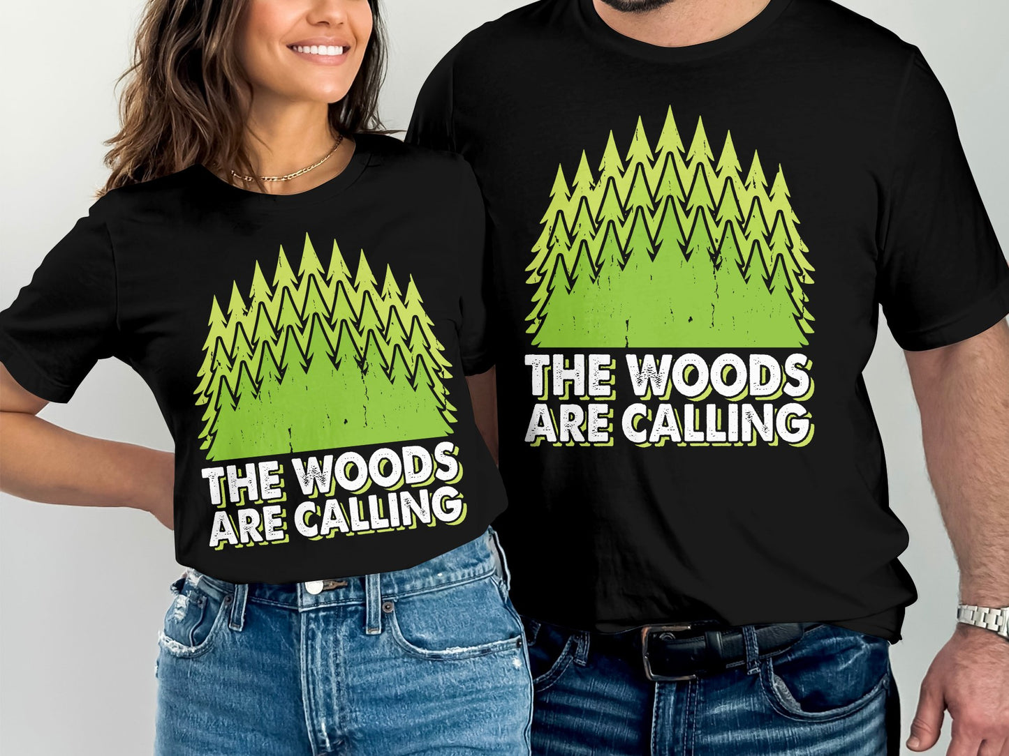 Black t-shirts with green pine trees and "The Woods Are Calling" text.