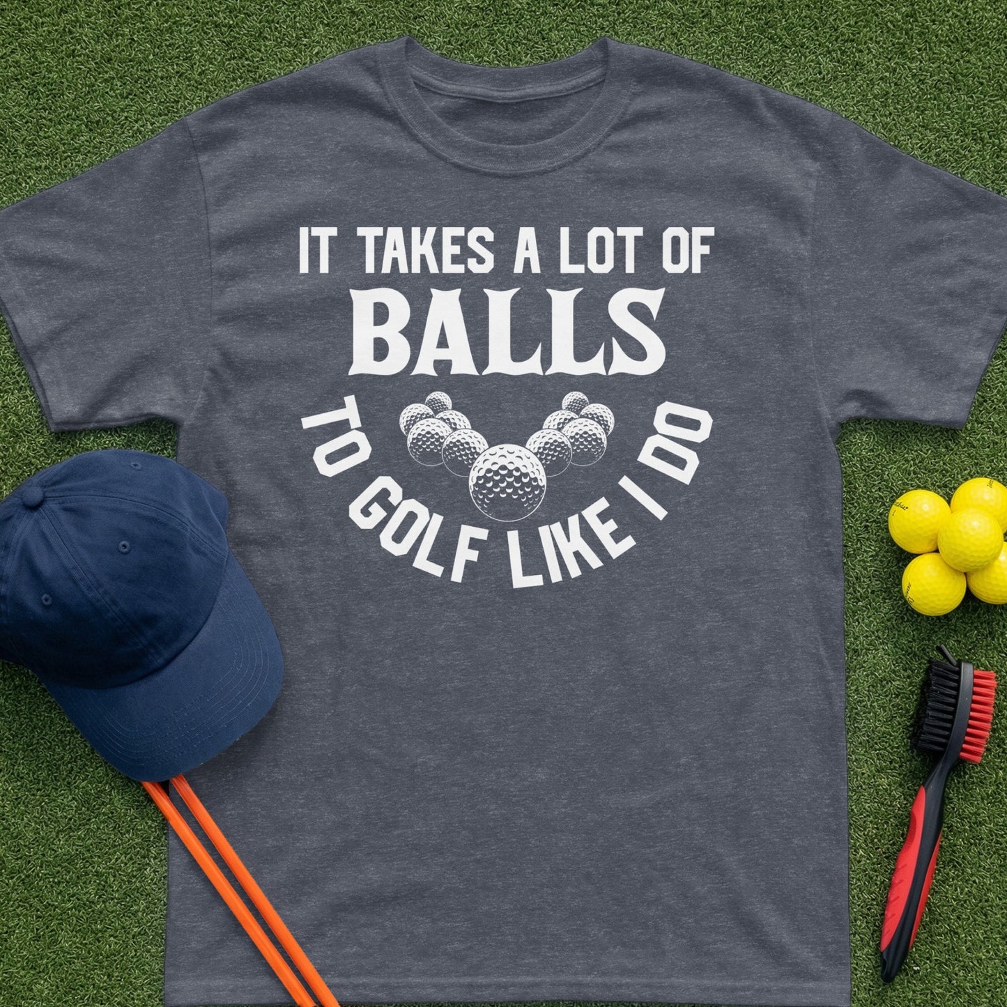Dark gray t-shirt with white text "IT TAKES A LOT OF BALLS TO GOLF LIKE I DO".