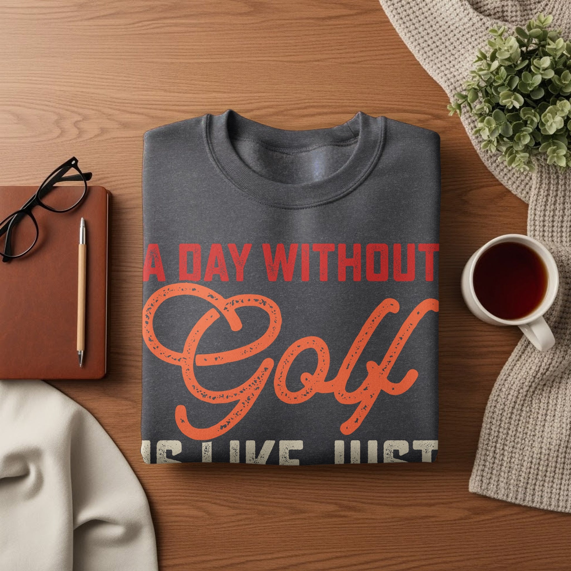 Dark gray sweatshirt with "A Day Without Golf" text on a wooden surface.