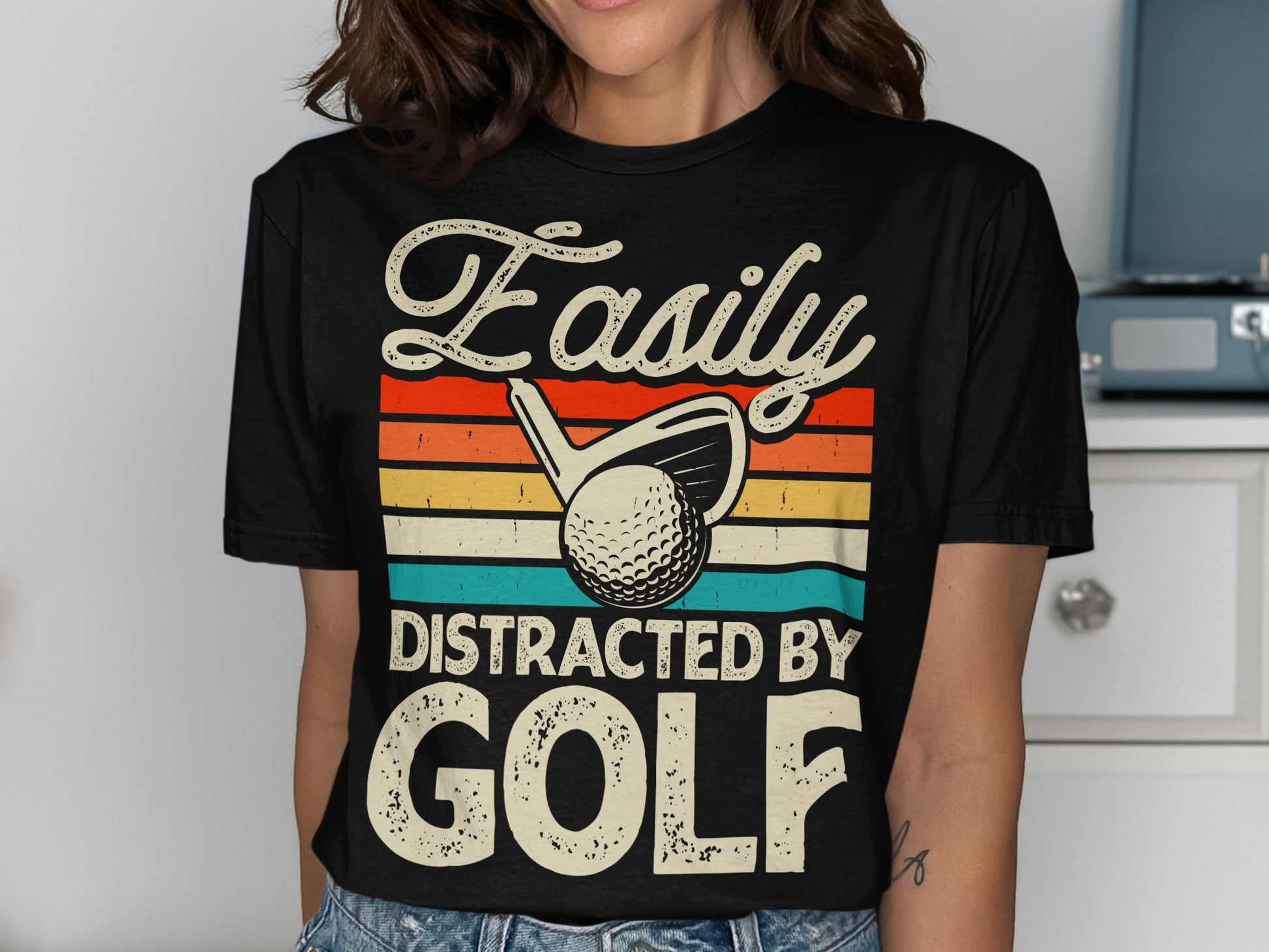 Black t-shirt with "Easily Distracted By Golf" text and golf ball graphic.