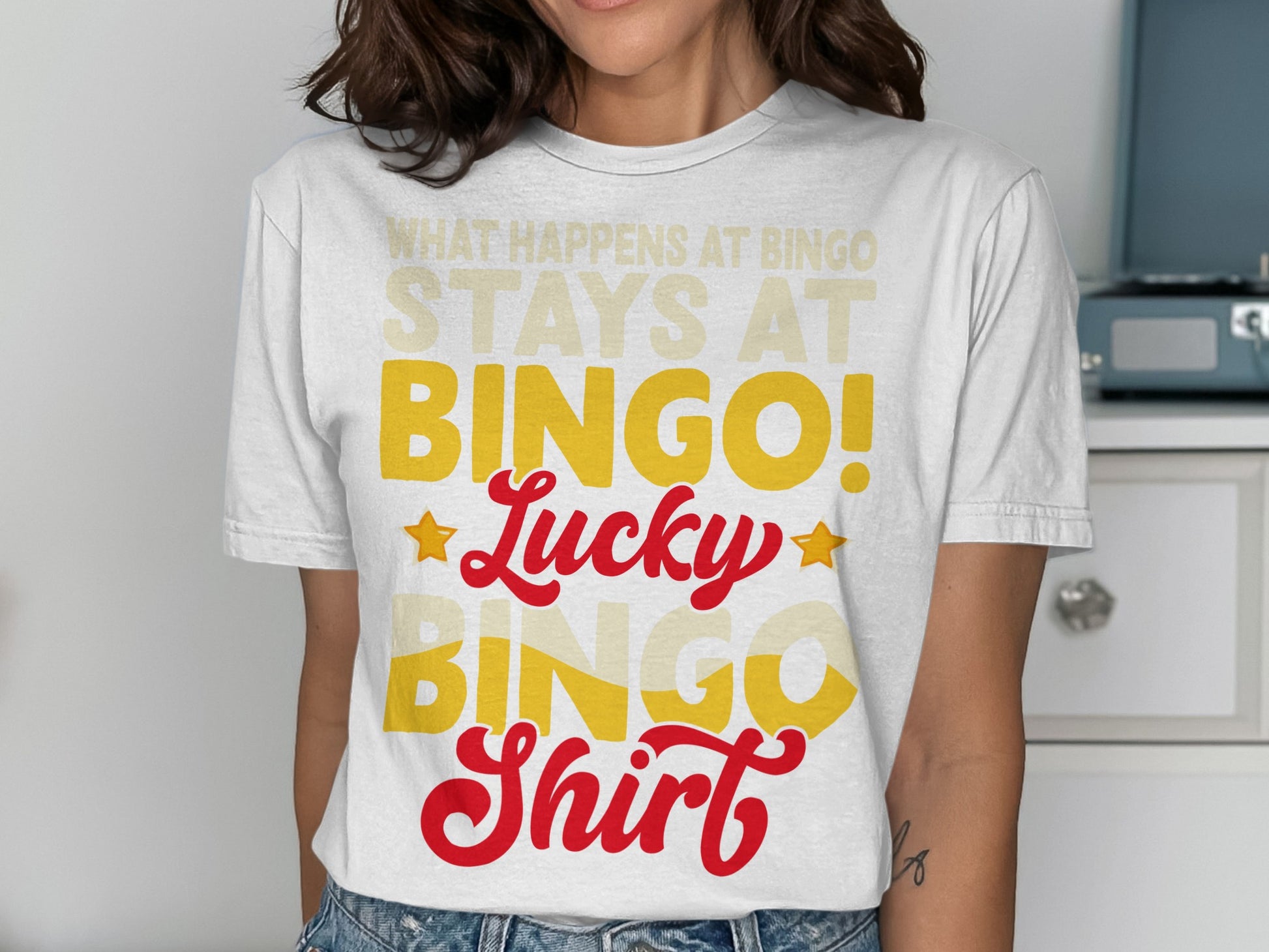 White t-shirt with "What Happens at Bingo Stays at Bingo!" in yellow text.