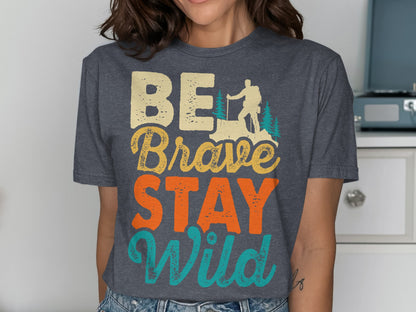 BE Brave STAY Wild text with hiker and mountain graphic on a charcoal t-shirt.