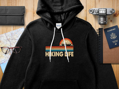 Black hoodie with "Hiking Life" and mountain graphic, compass, passport, glasses.