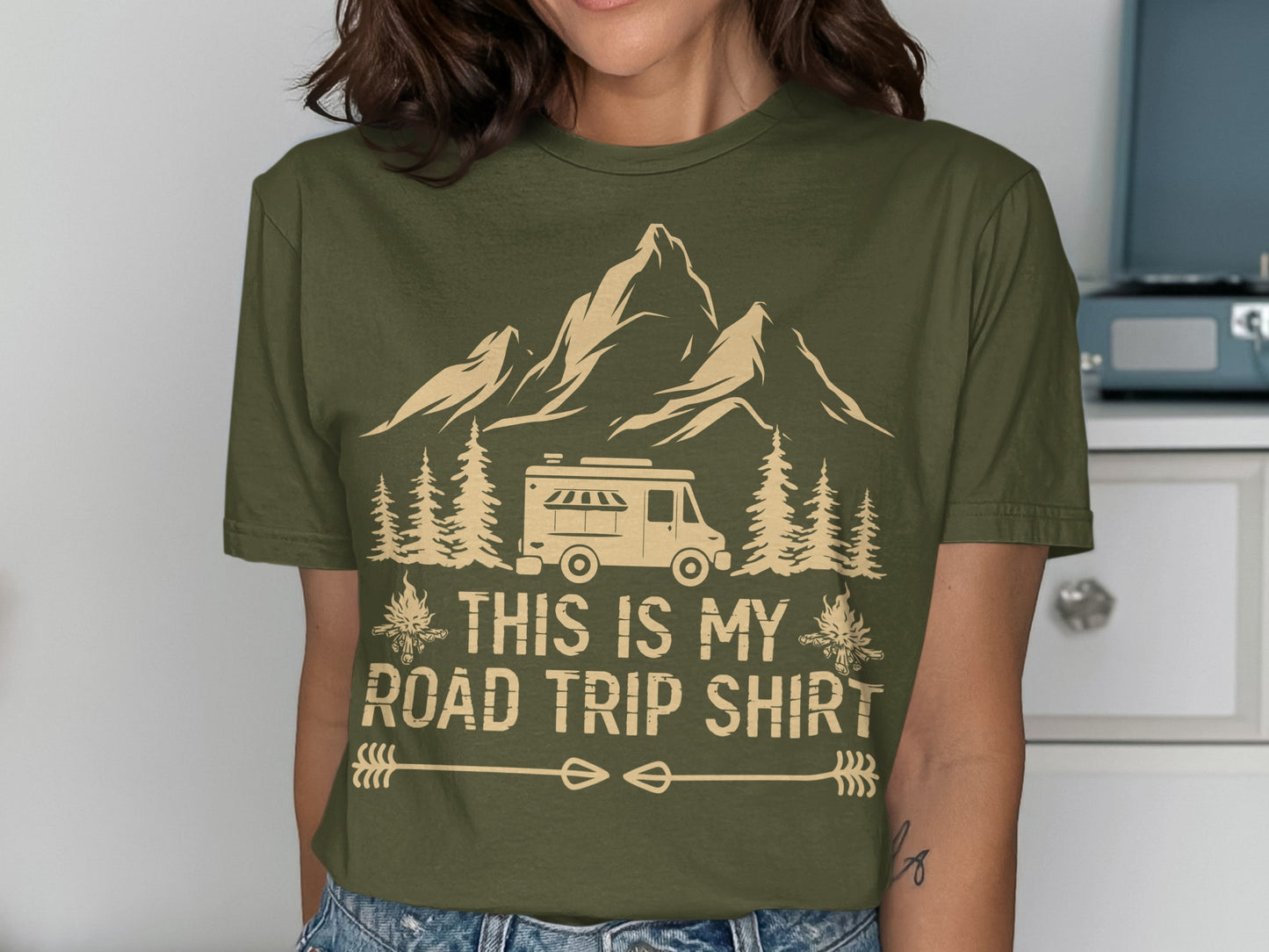 Olive green t-shirt with a camper, mountains, trees, and the text "THIS IS MY ROAD TRIP SHIRT".