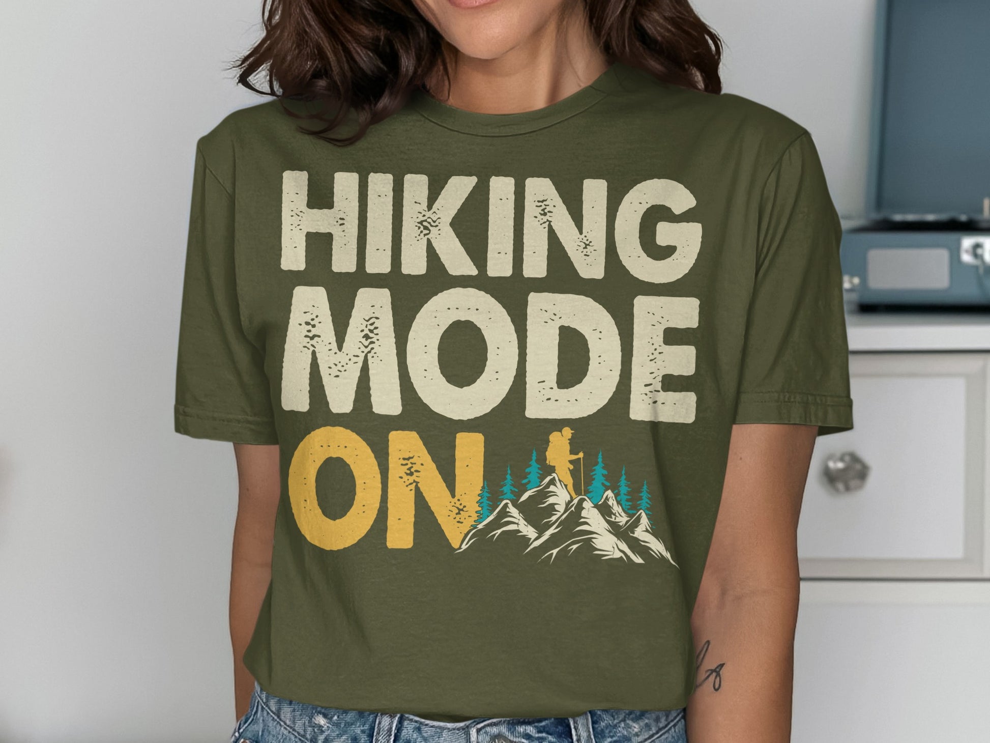 Olive green t-shirt with "Hiking Mode On" text and mountain graphic.