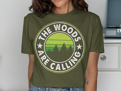 Olive green t-shirt with "The Woods Are Calling" text and forest silhouette.