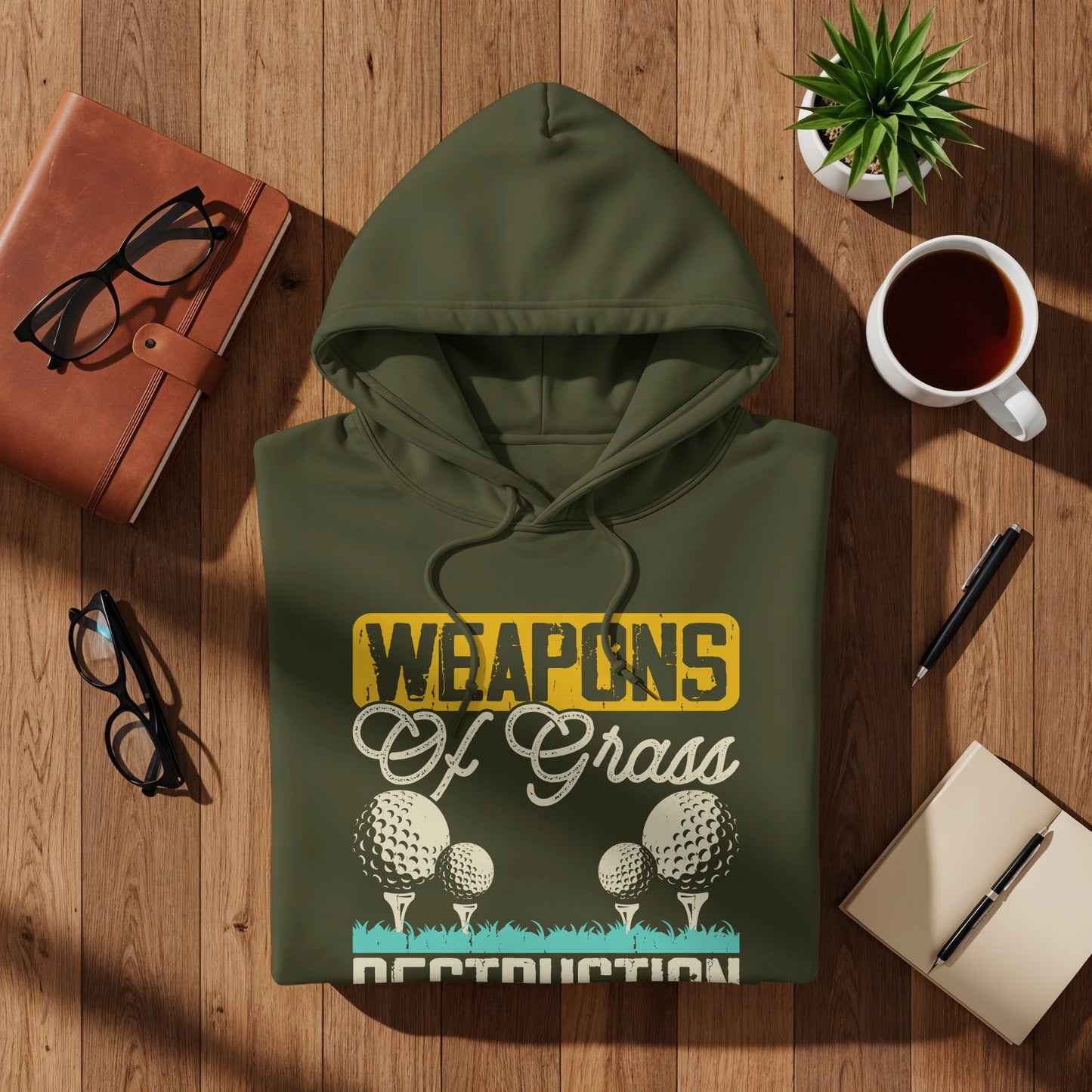 Green hoodie with "Weapons Of Grass Destruction" text and golf balls.
