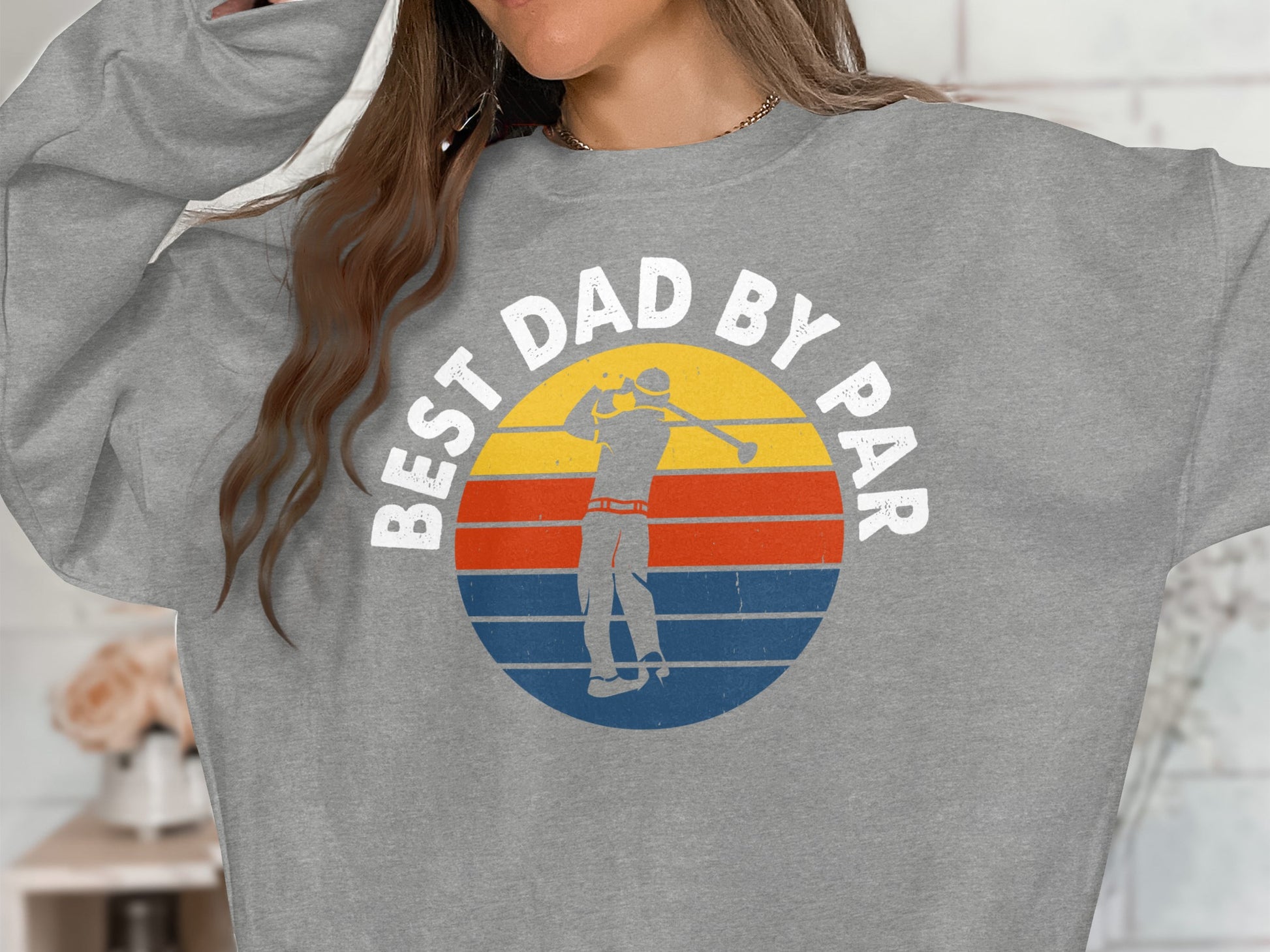 Gray sweatshirt with "BEST DAD BY PAR" text and a golfer in a retro sunset graphic.