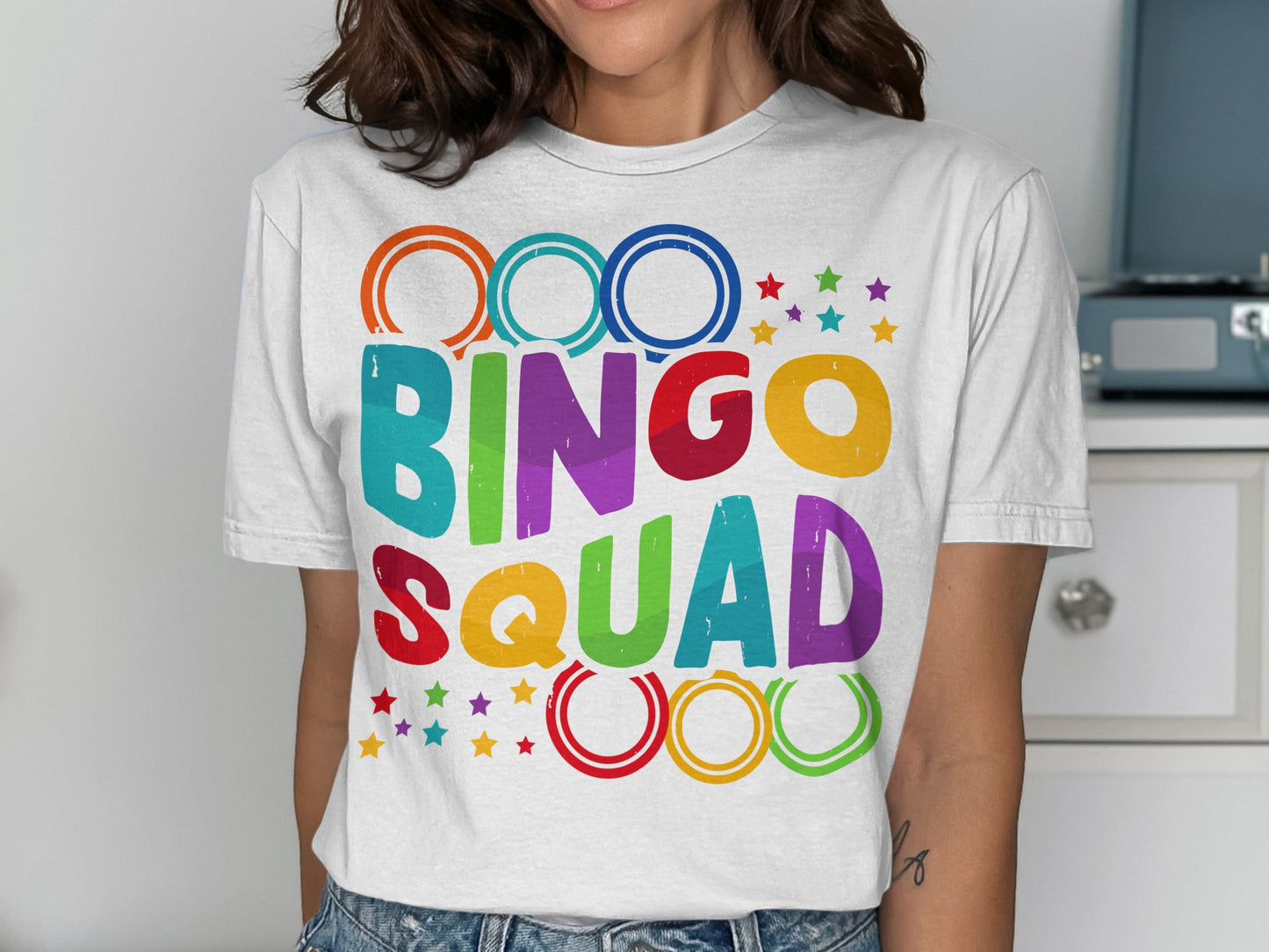White t-shirt with colorful "BINGO SQUAD" text and rings.