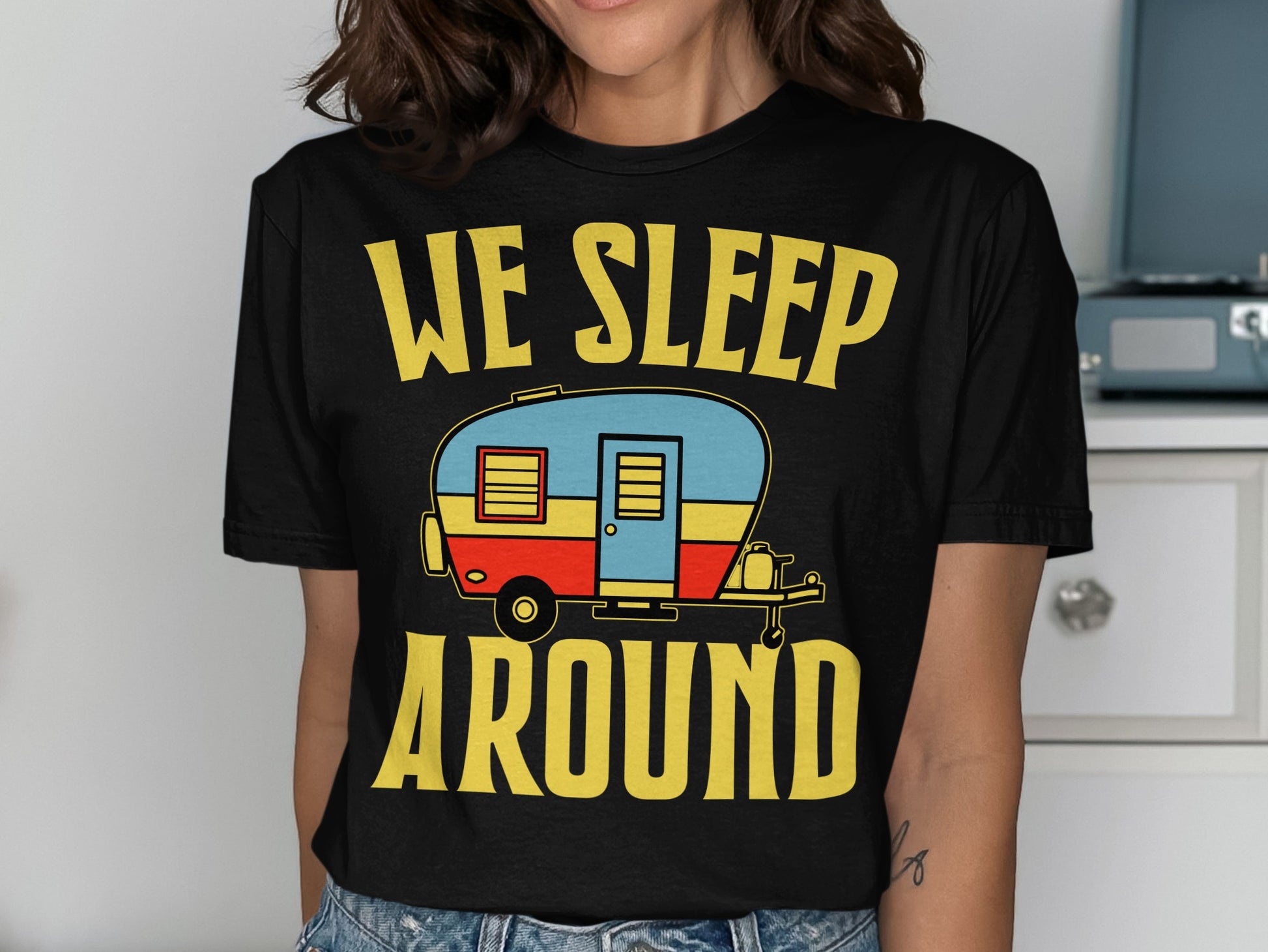 Black t-shirt with yellow text "WE SLEEP AROUND" and a cartoon camper.