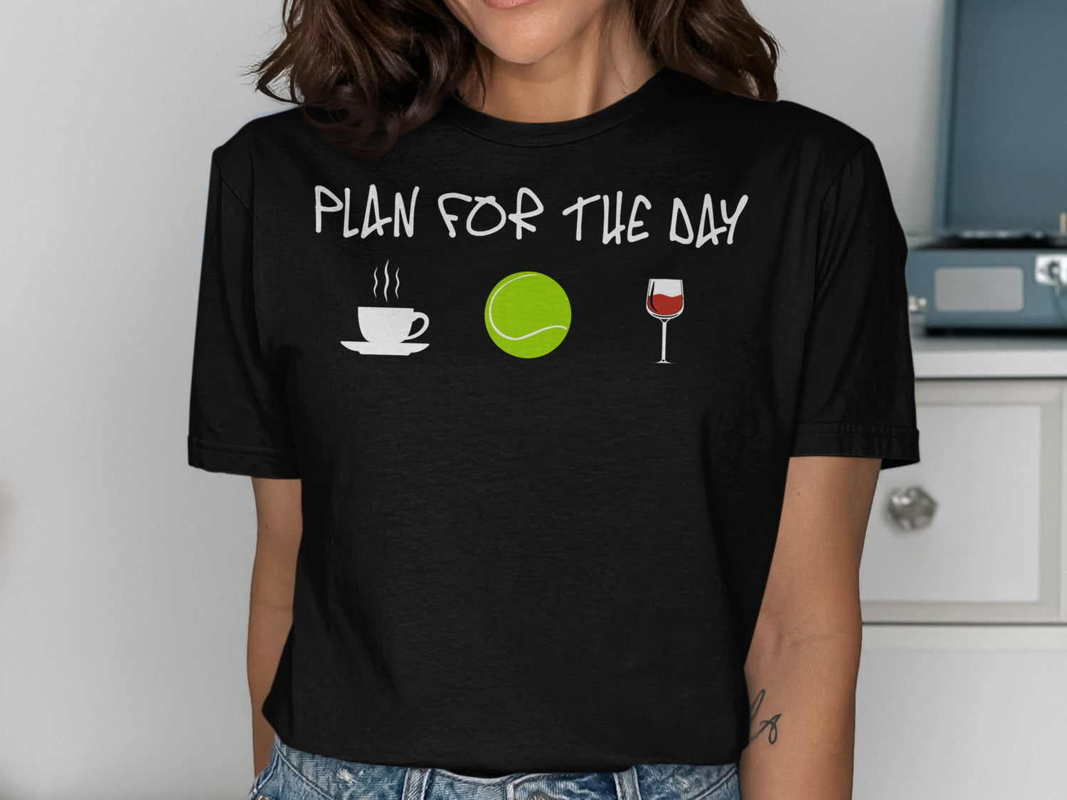 T-shirt with icons: coffee cup, tennis ball, wine glass, and text "plan for the day."