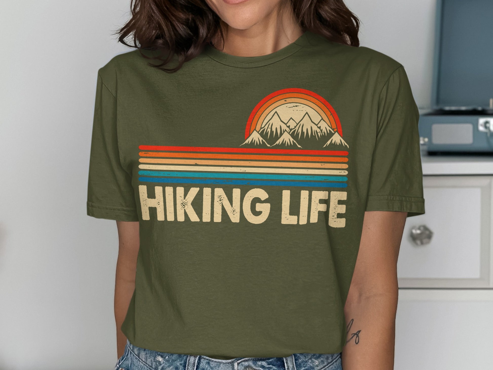 Olive green t-shirt with "Hiking Life" text and a retro mountain sunset graphic.