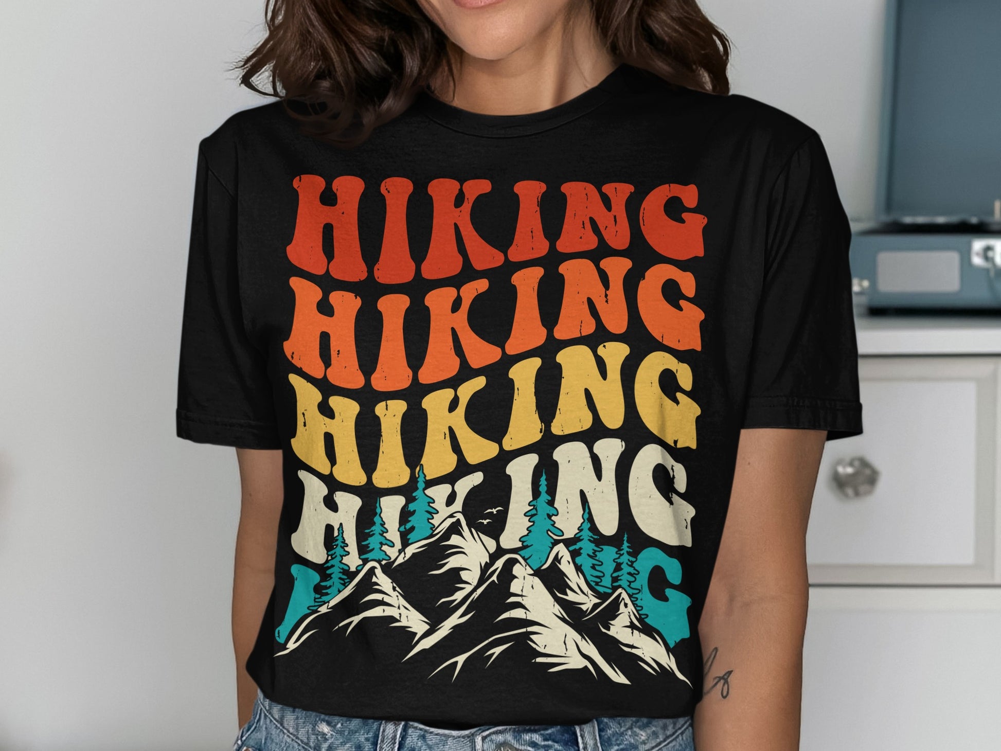 Retro "Hiking" text over mountain and tree graphic on a t-shirt.