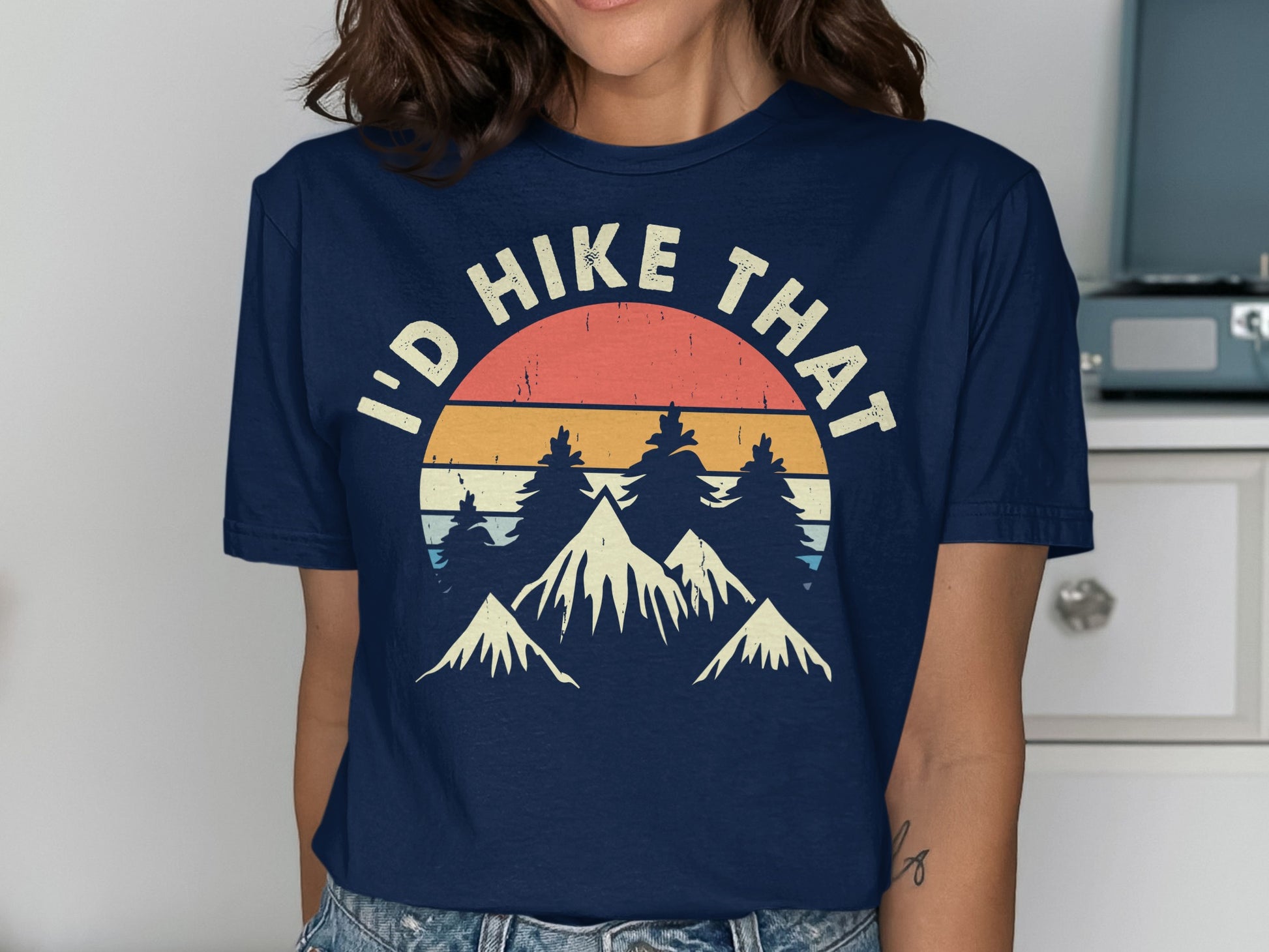 Navy t-shirt with "I'd Hike That" text over a mountain and sunset graphic.