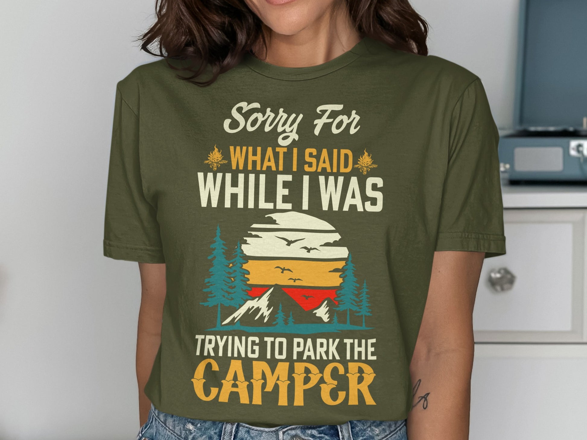 Olive green t-shirt with "Sorry For While I Was Trying To Park The Camper" text and sunset graphic.