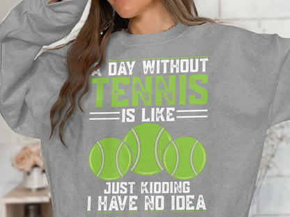 Gray sweatshirt with "A day without tennis is like just kidding I have no idea" and tennis balls.