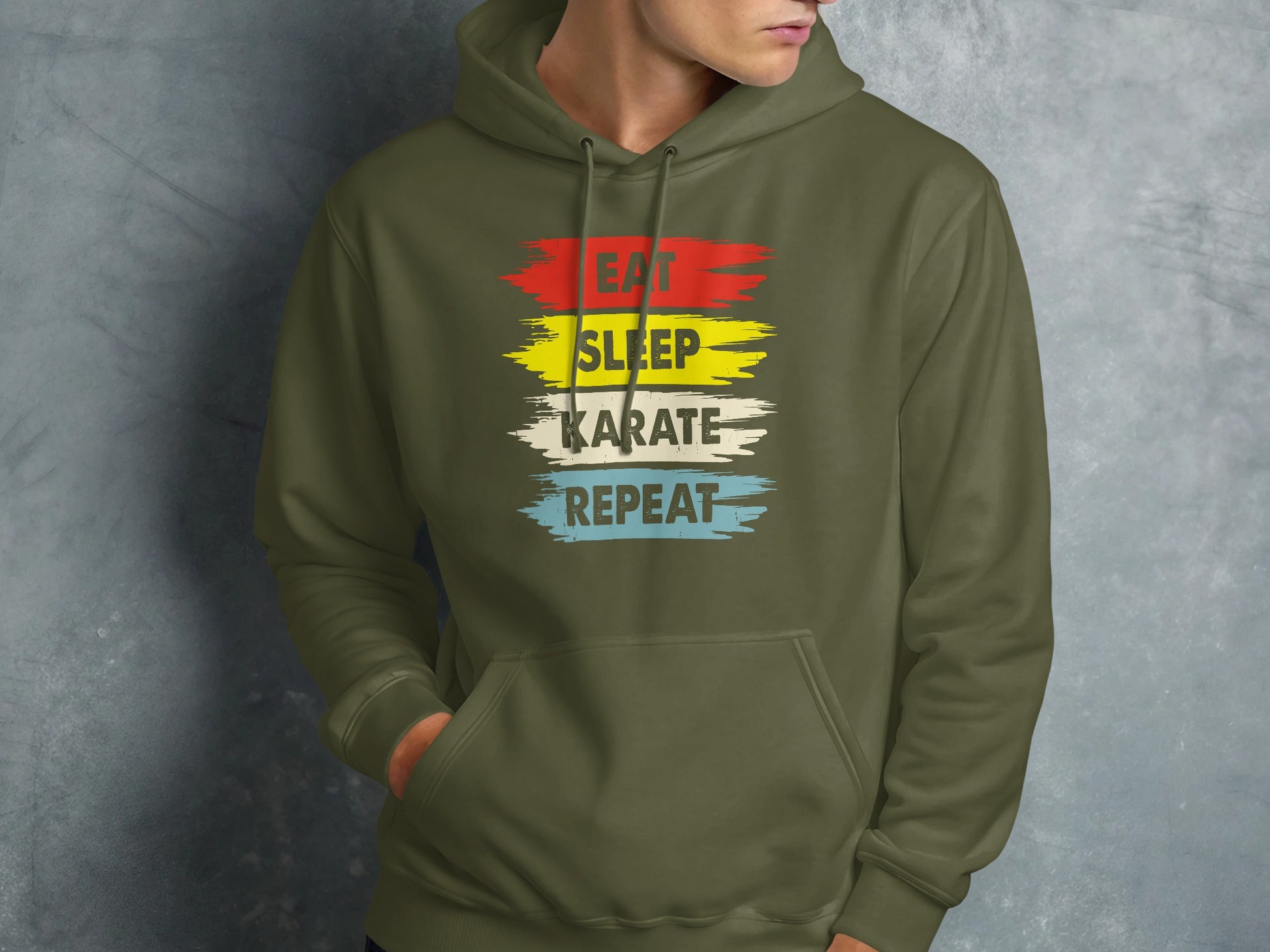 Olive green hoodie with "EAT SLEEP KARATE REPEAT" text in red, yellow, white, and blue stripes.