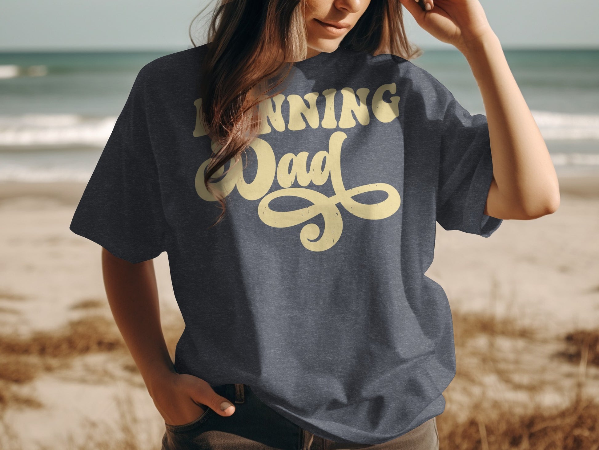 Dark grey t-shirt with "Running Dad" in yellow cursive on a beach background.