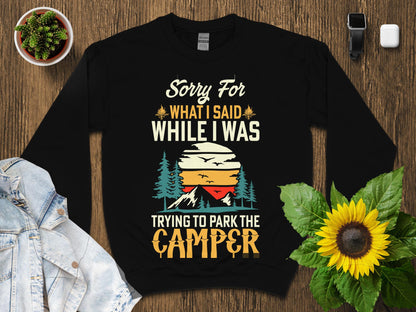 Black sweatshirt with "Sorry for what I said while I was trying to park the camper" text and sunset graphic.