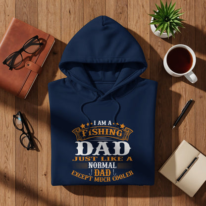 Navy hoodie with "Fishing Dad Except Much Cooler" text, flat lay on wood.