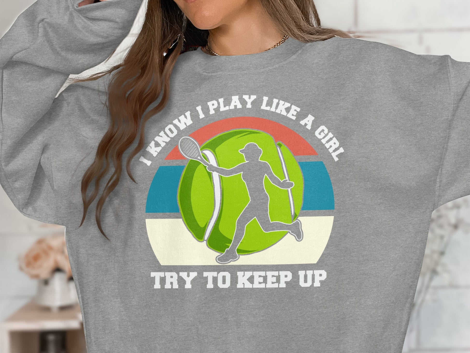 Gray sweatshirt with "I Know I Play Like A Girl Try To Keep Up" text and tennis graphic.