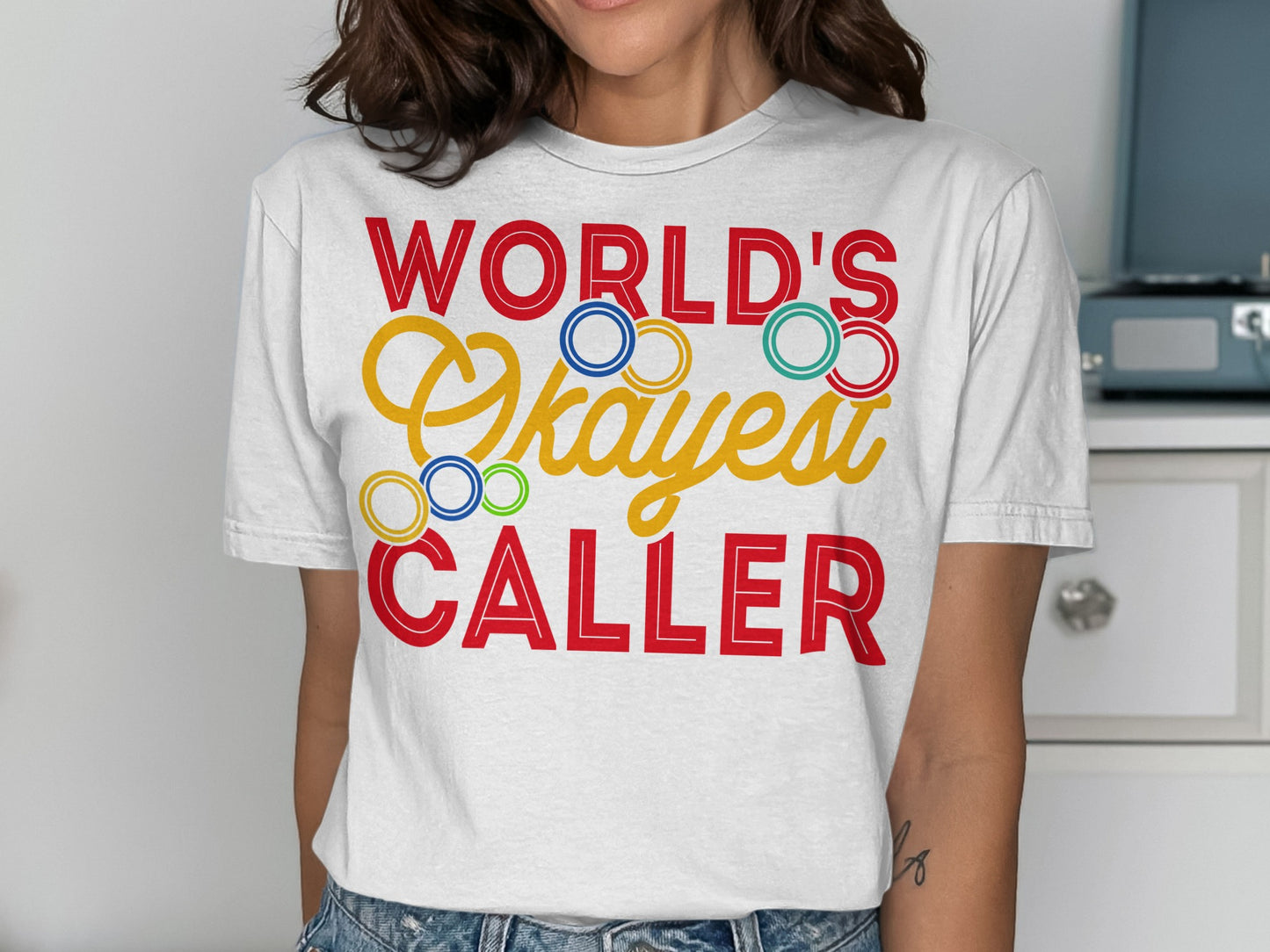 White t-shirt with "WORLD'S Okayest CALLER" text in colorful lettering.