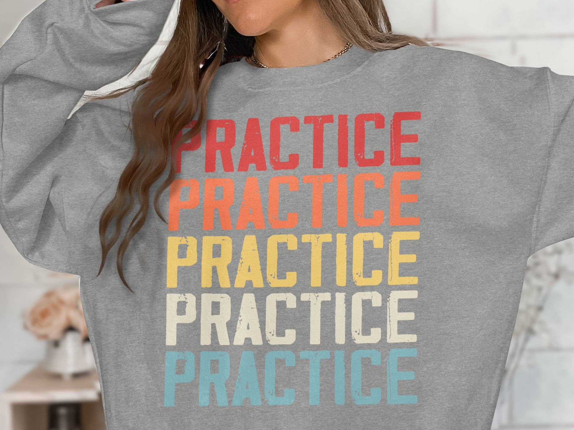 Grey sweatshirt with "PRACTICE" repeated in red, orange, yellow, and blue.