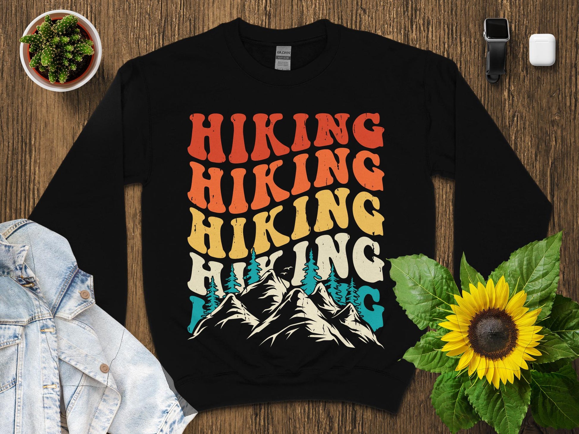 Black sweatshirt with "Hiking" repeated in retro font over mountains and trees.