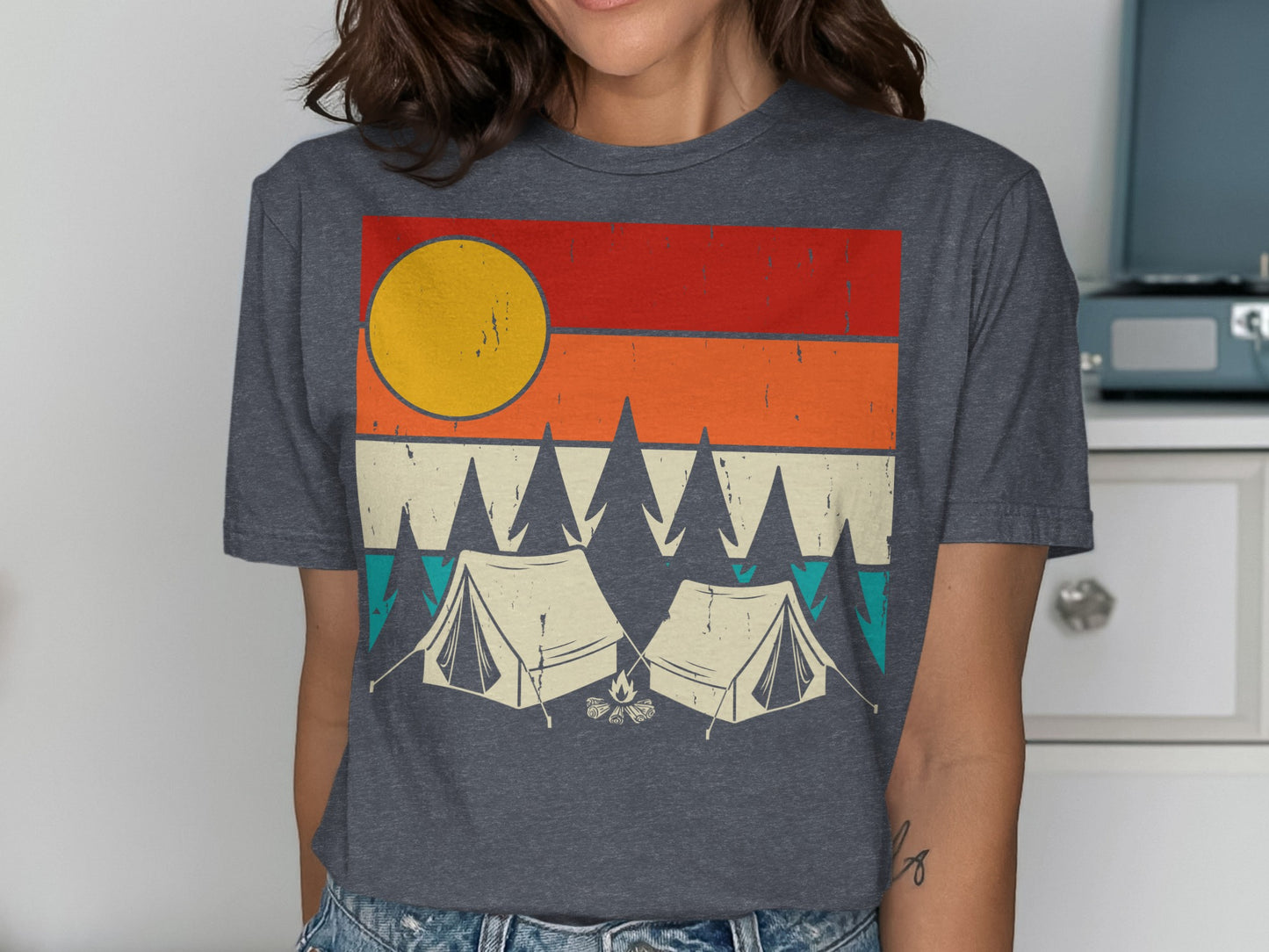 Graphic t-shirt with two tents, trees, and a sun on a striped background.