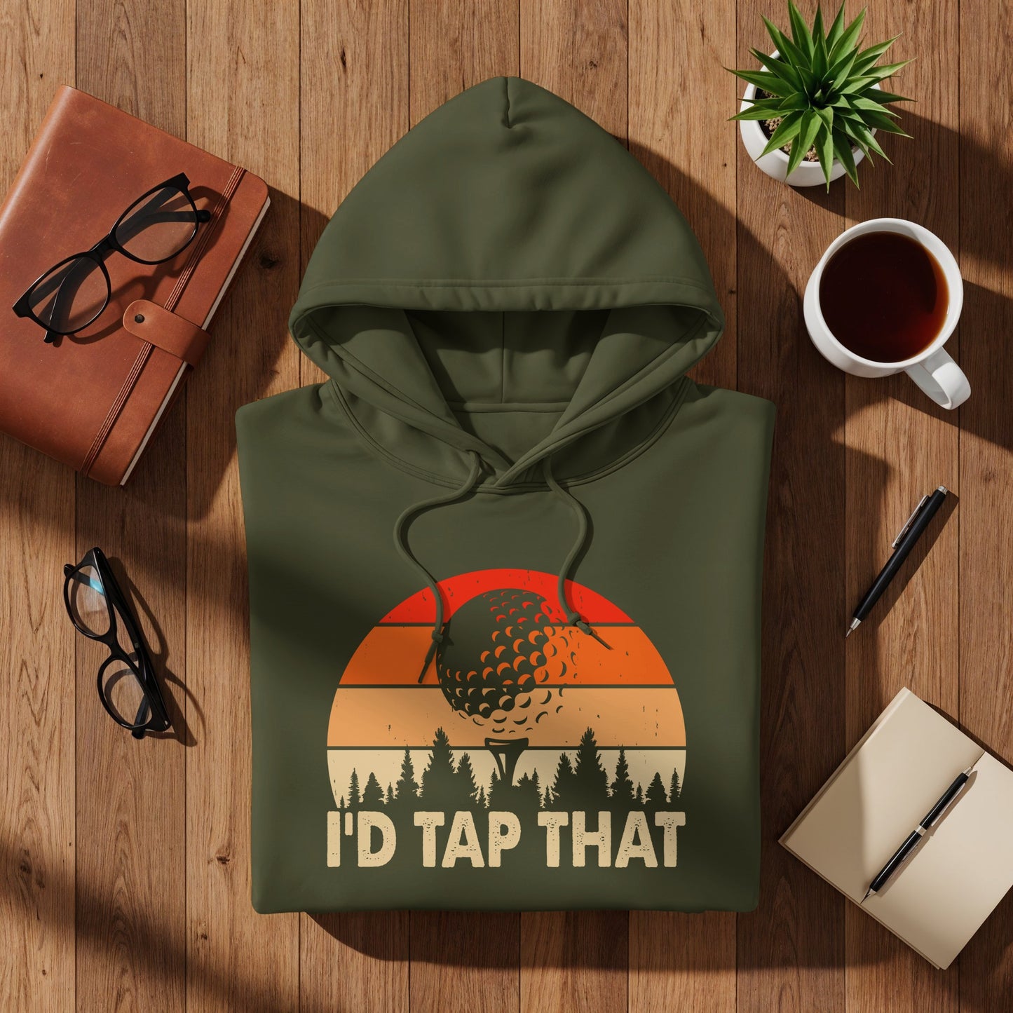 Olive green hoodie with "I'd Tap That" text and golf ball sunset graphic.