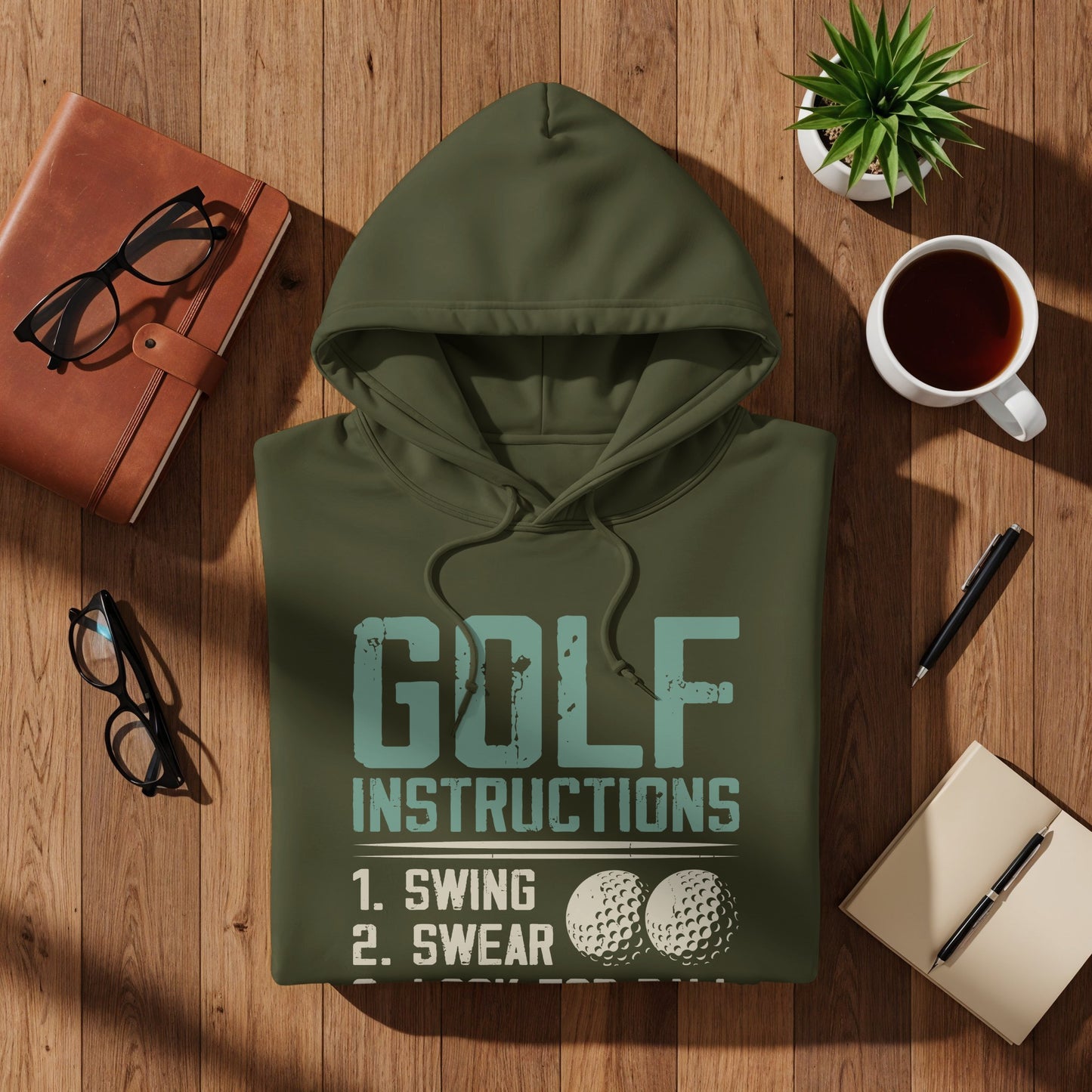 Olive green hoodie with "GOLF INSTRUCTIONS" and "1. SWING 2. SWEAR" text and golf balls.