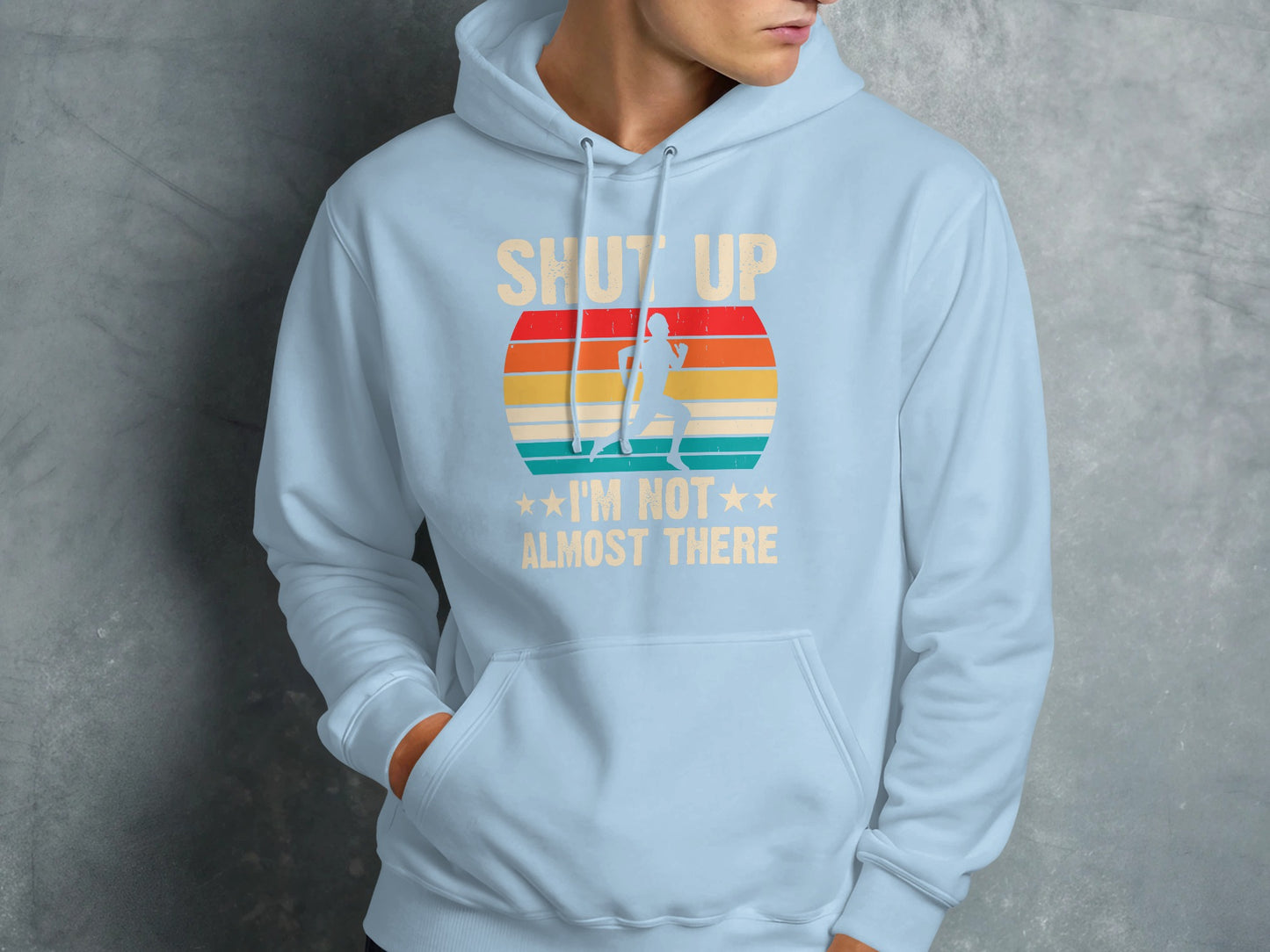 Light blue hoodie with text "SHUT UP I'M NOT *** ALMOST THERE" and retro sunset graphic.
