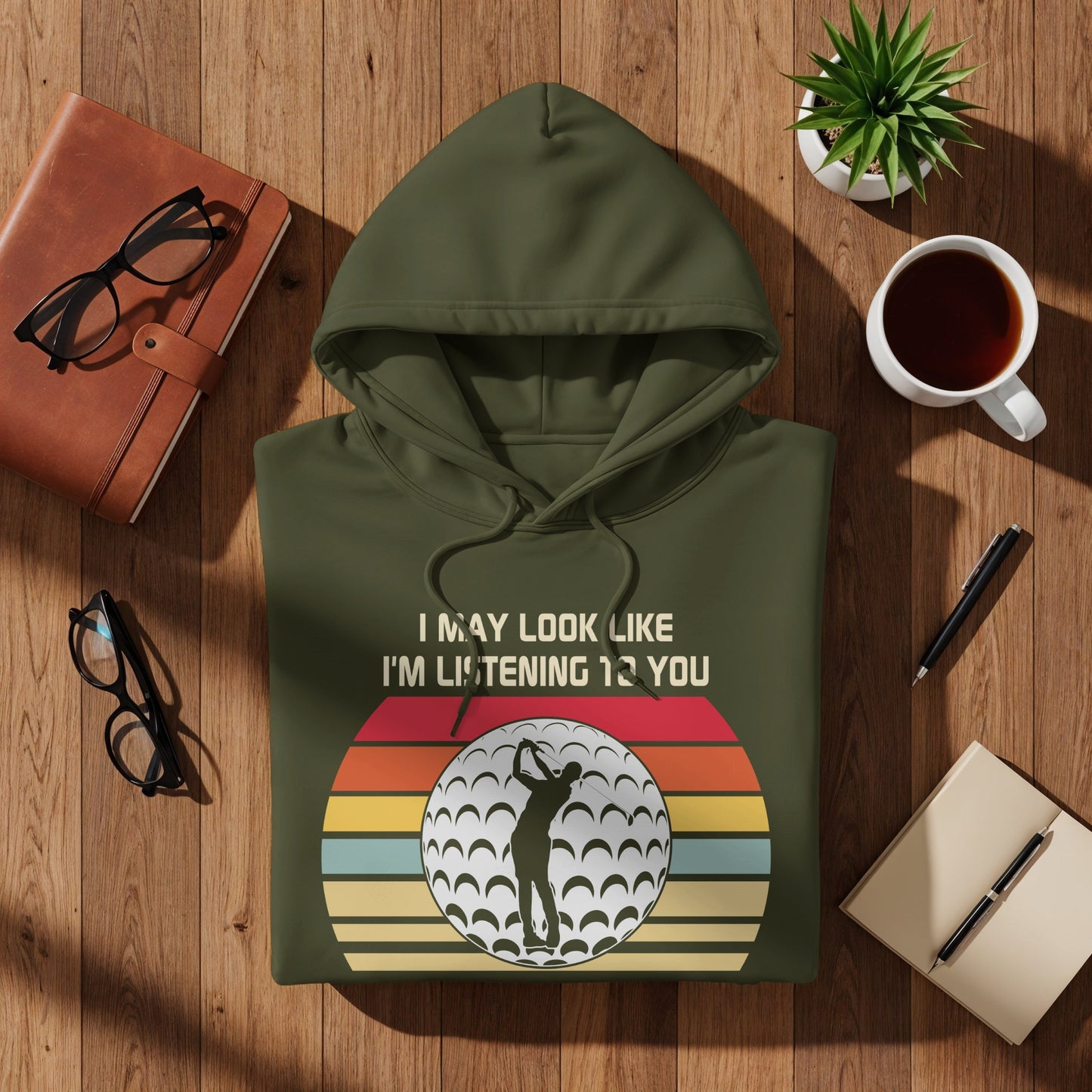 Green hoodie with "I may look like I'm listening 12 you" and golf ball graphic.
